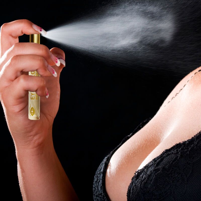 Persona che spruzza profumo. Visibili: flacone con scritta Eye of Love, scollatura, unghie. Sfondo nero.