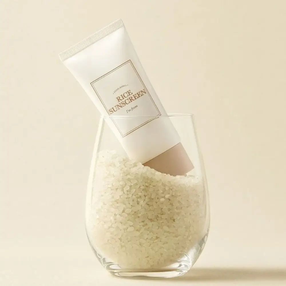 Tubo crema in vetro con riso. Scritta « Rice Sunscreen » e « I'm from ». Tappo beige.