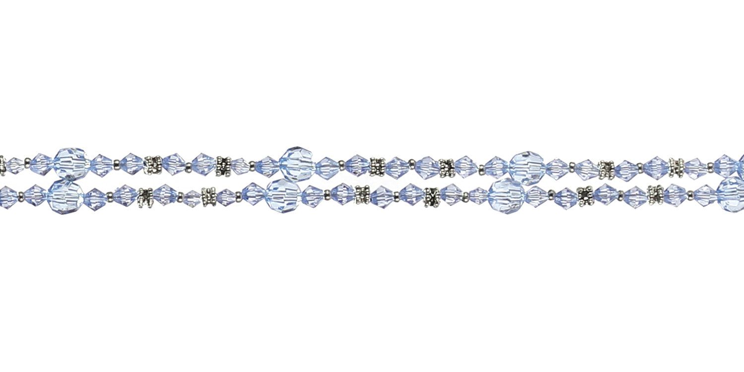 Primo piano della catenina per occhiali con perline blu e dettagli metallici. Dettagli della struttura delle perline visibili.