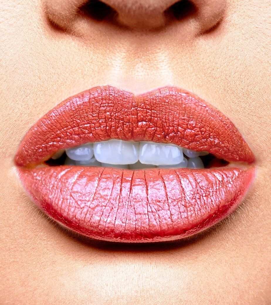 Primo piano di labbra con rossetto rosso e denti visibili.