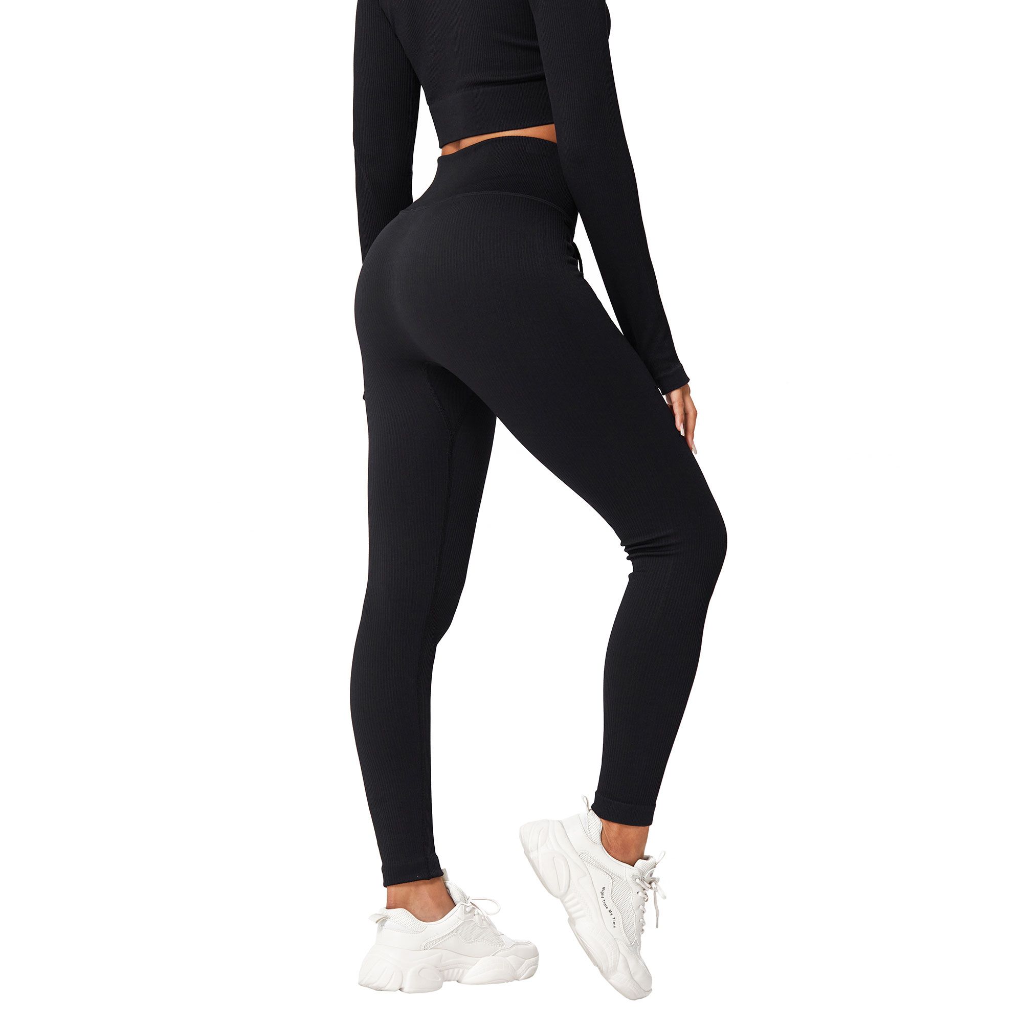 Leggings neri a coste e top a maniche lunghe con fori per i pollici, indossati con sneakers bianche.