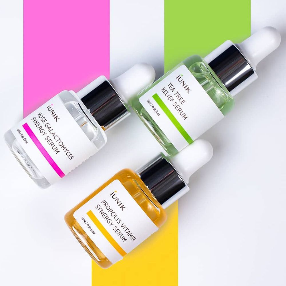 Tre flaconi di siero con pipette. Colori: rosa, verde, giallo. Testo: iUNIK, Rose, Tea Tree, Propolis. Su sfondo colorato.