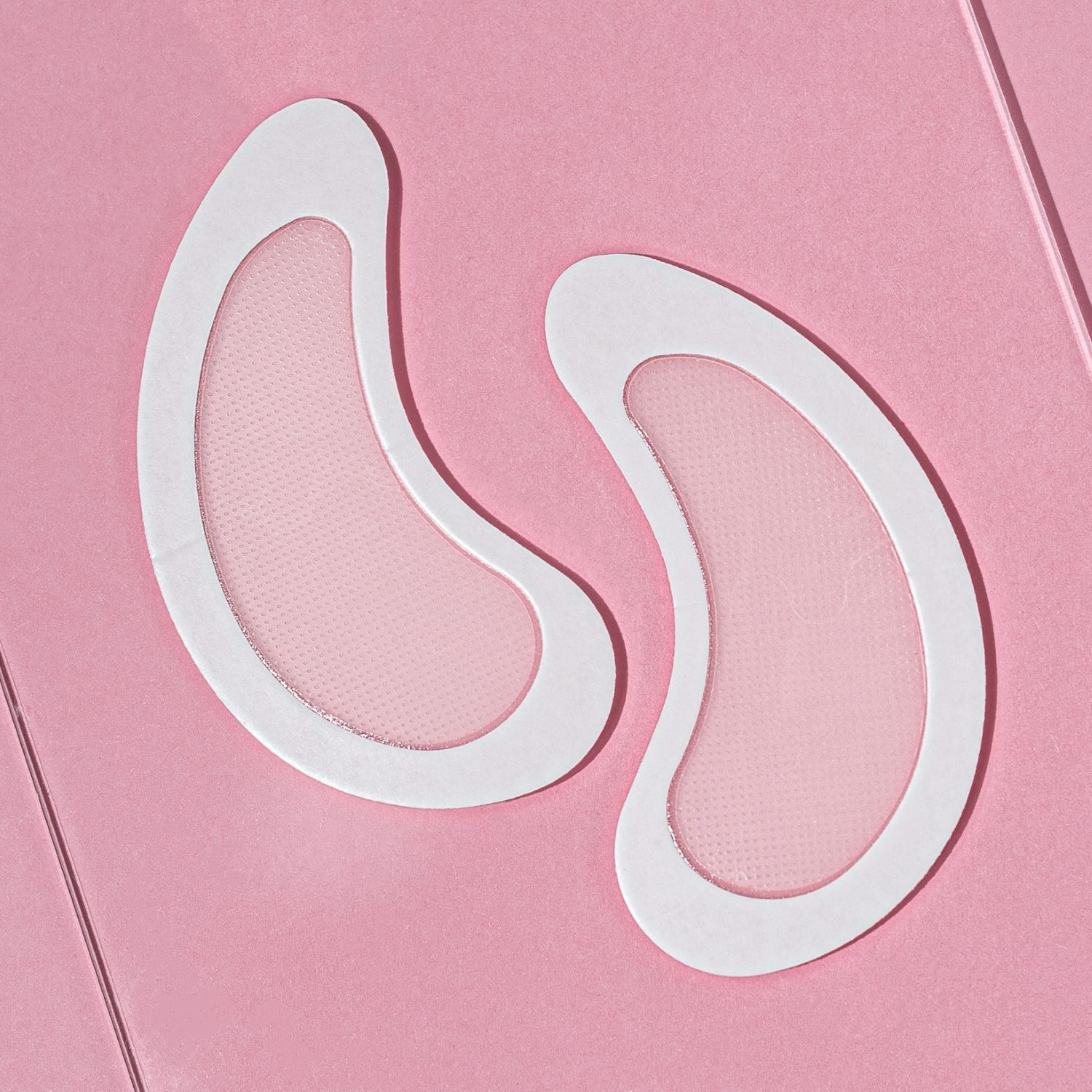 Due patch bianchi a forma di occhio con una rete chiara. Su sfondo rosa.