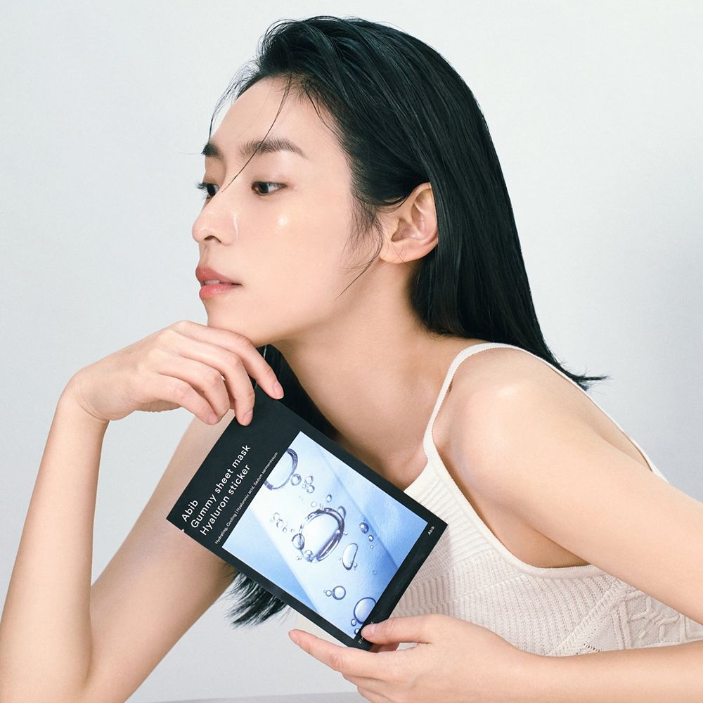 Persona che tiene una confezione nera con nome del prodotto e ingredienti. La persona indossa una canotta.