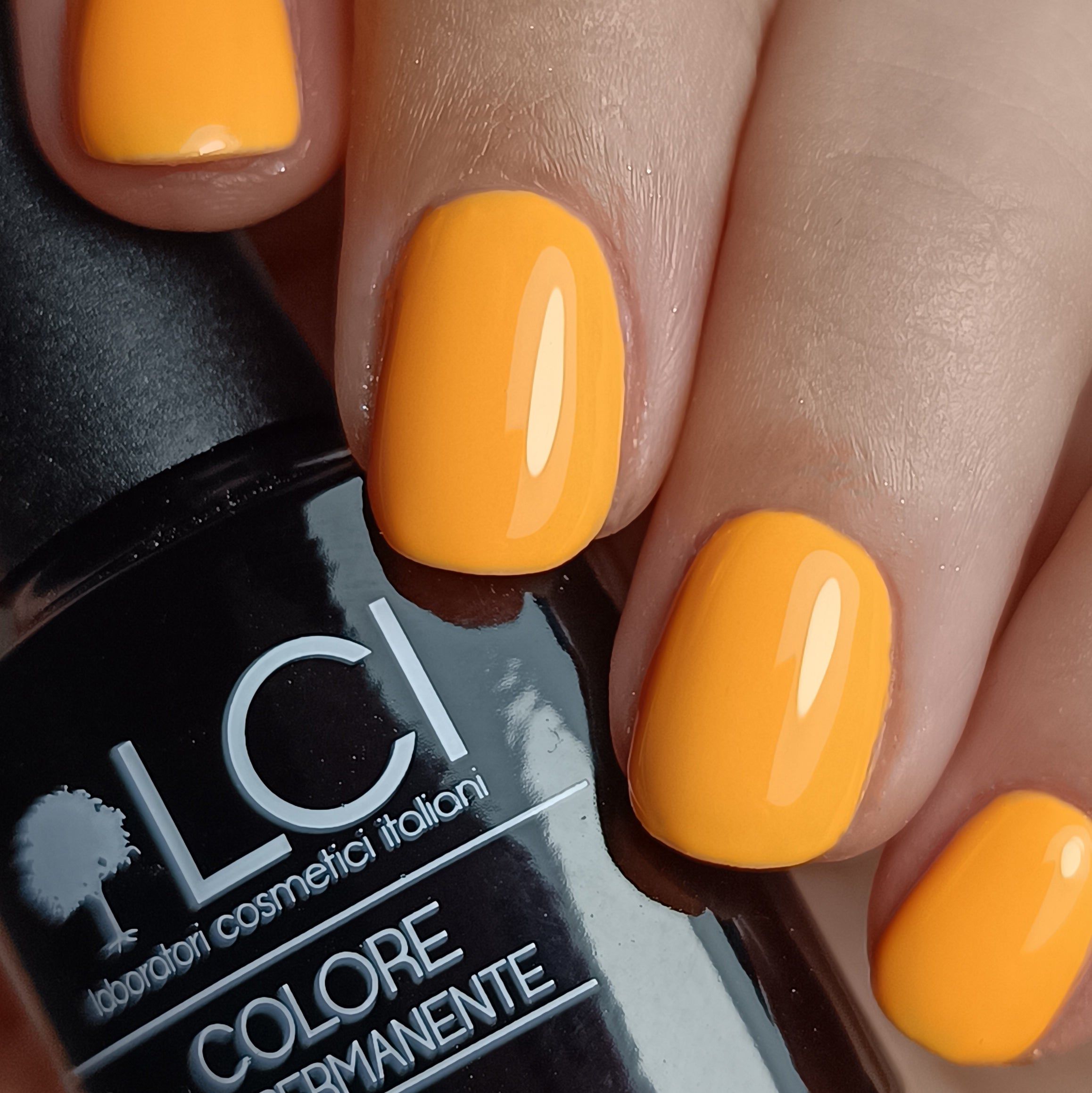 Mano con unghie smaltate di arancione. Flacone nero con logo LCI e scritta Colore Semipermanente.
