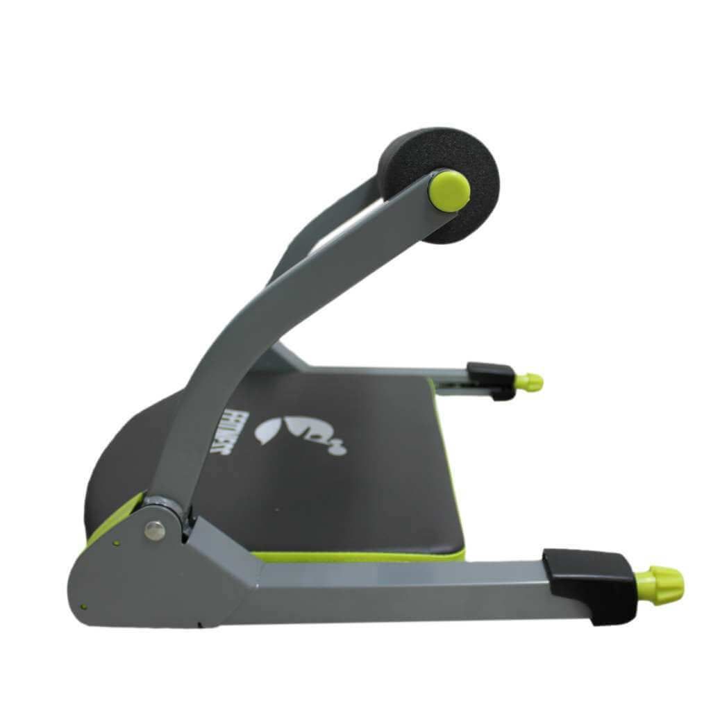 Attrezzo fitness, vista laterale. Telaio grigio, dettagli verdi, rullo nero. Seduta imbottita con logo FFitness.