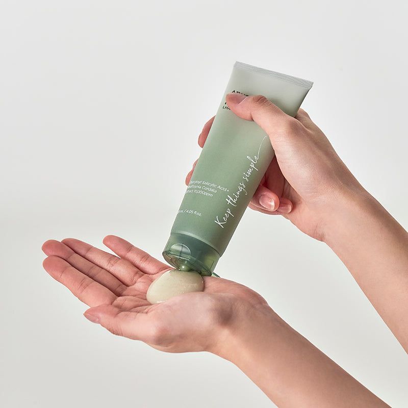 Mani che tengono un tubo verde. Prodotto spremuto sul palmo. Scritta: ANUA, HEARTLEAF LHA MOISTURE PEELING GEL.
