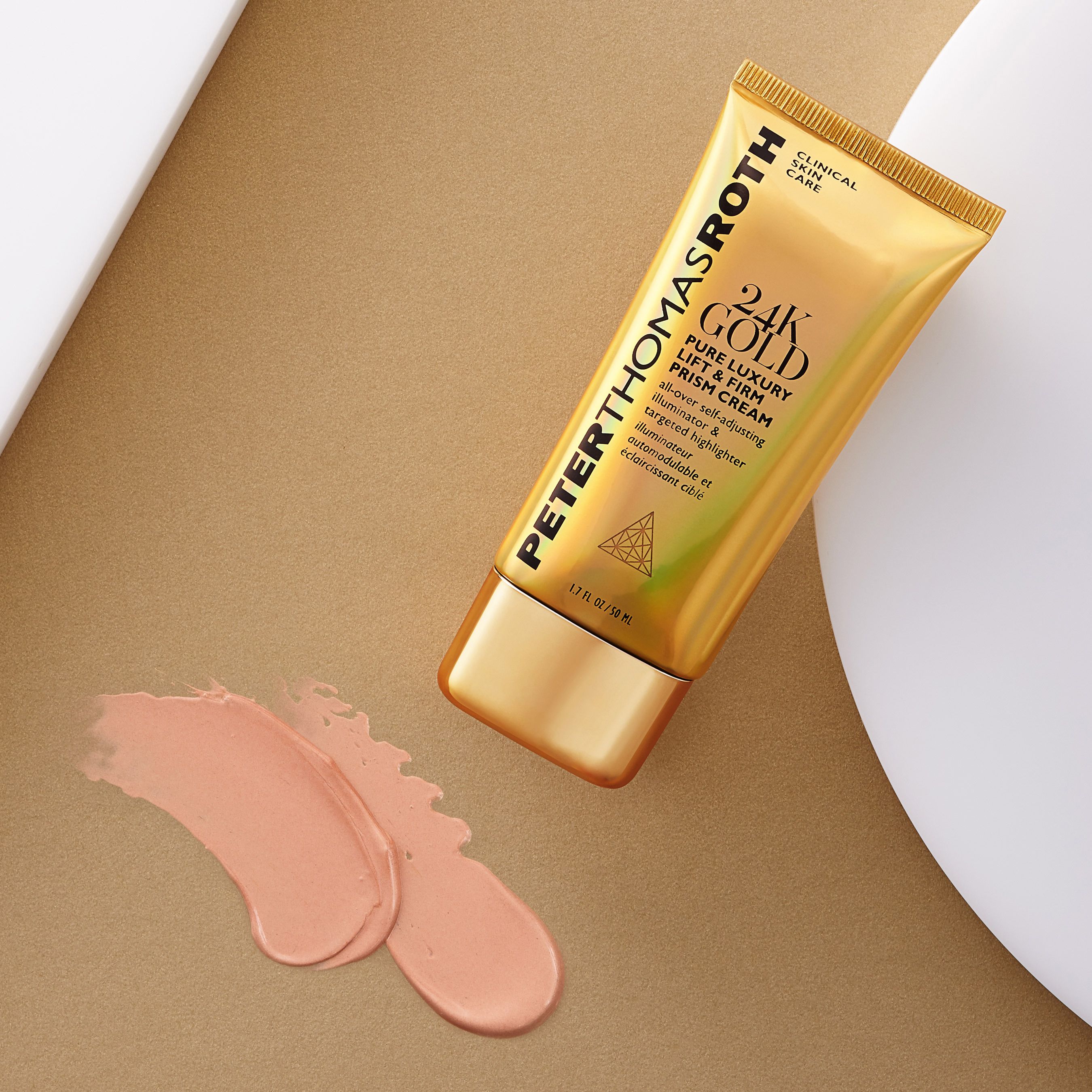 Tubo dorato con nome del prodotto e testo. Peter Thomas Roth 24K Gold Pure Luxury Lift & Firm Prism Cream. Flusso di crema accanto.