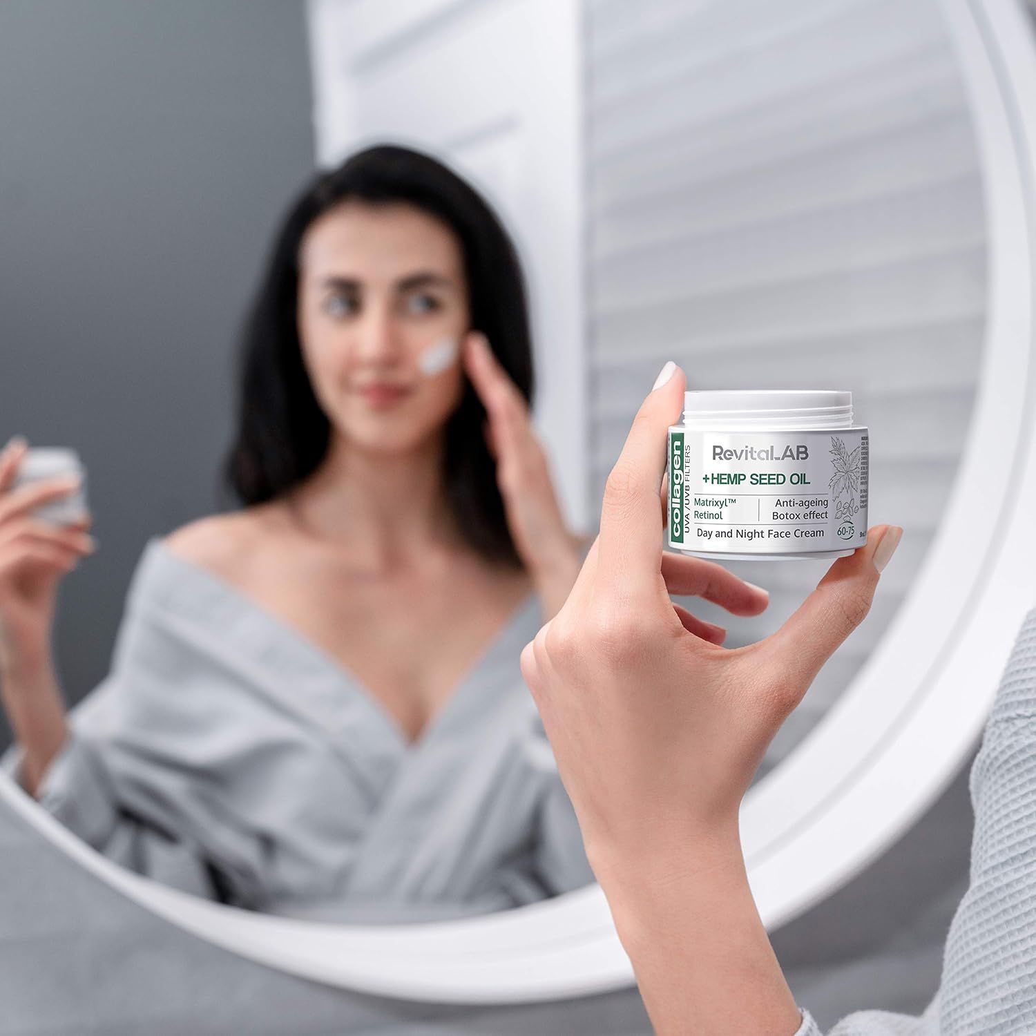 Donna davanti allo specchio. Tiene un vasetto bianco. Scritta: RevitaLAB + Olio di semi di canapa, Matrixyl, Retinolo, Anti-età, Effetto Botox. Crema giorno e notte.
