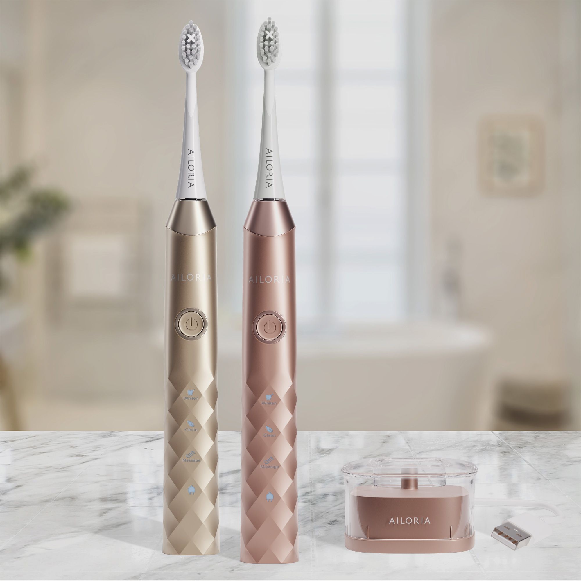 Due spazzolini sonici dorati e rosa con base di ricarica. Logo AILORIA visibile.