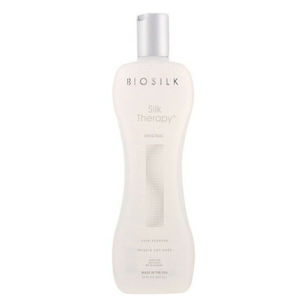 Flacone Biosilk Silk Therapy. Design bianco, sagomato, tappo argento. Testo: Silk Therapy Original, care essence, terapia con seda.