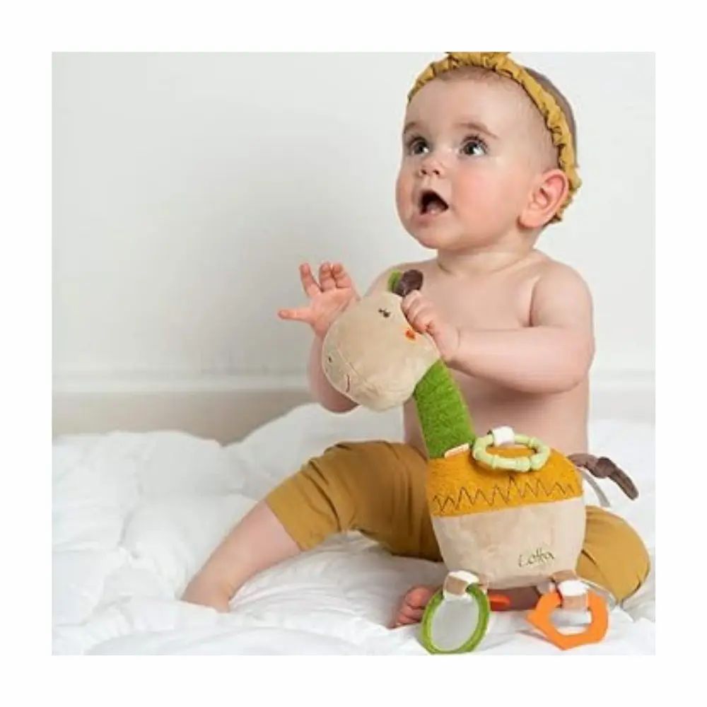 Bambino tiene in mano una giraffa di peluche. Beige, verde e giallo. Anelli e specchi. Scritta "Lotta". Il bambino indossa una fascia.