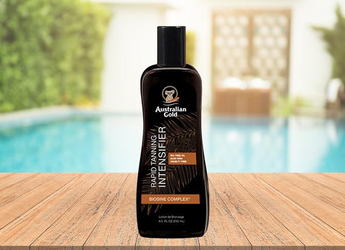 Flacone marrone su superficie in legno. Scritta: Australian Gold, Rapid Tanning Intensifier, Biosine Complex. Sfondo: piscina.