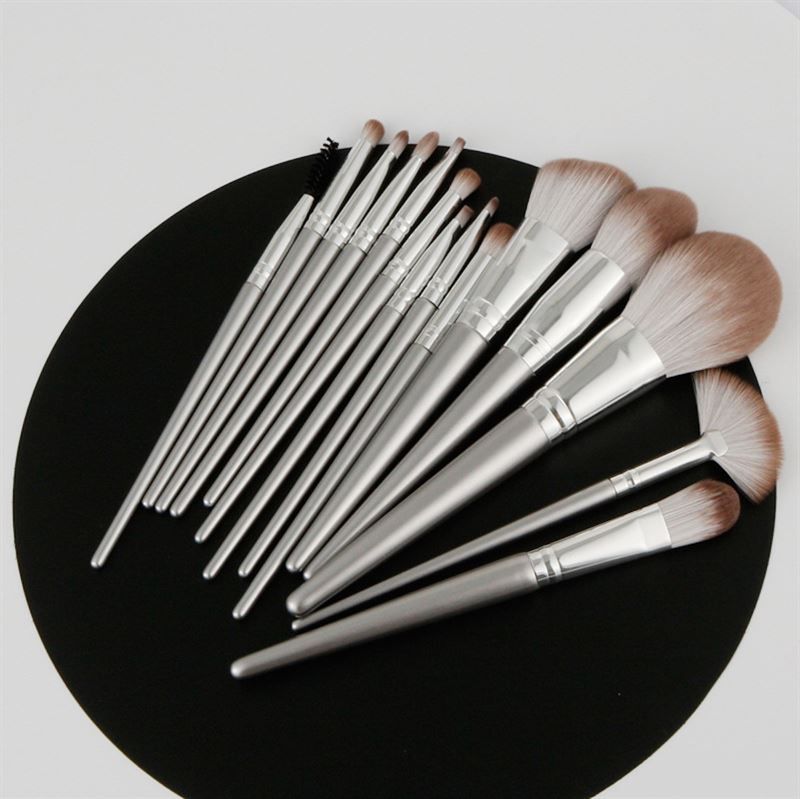 Set di pennelli per trucco su sfondo nero. Varie forme di pennelli con manici argentati.