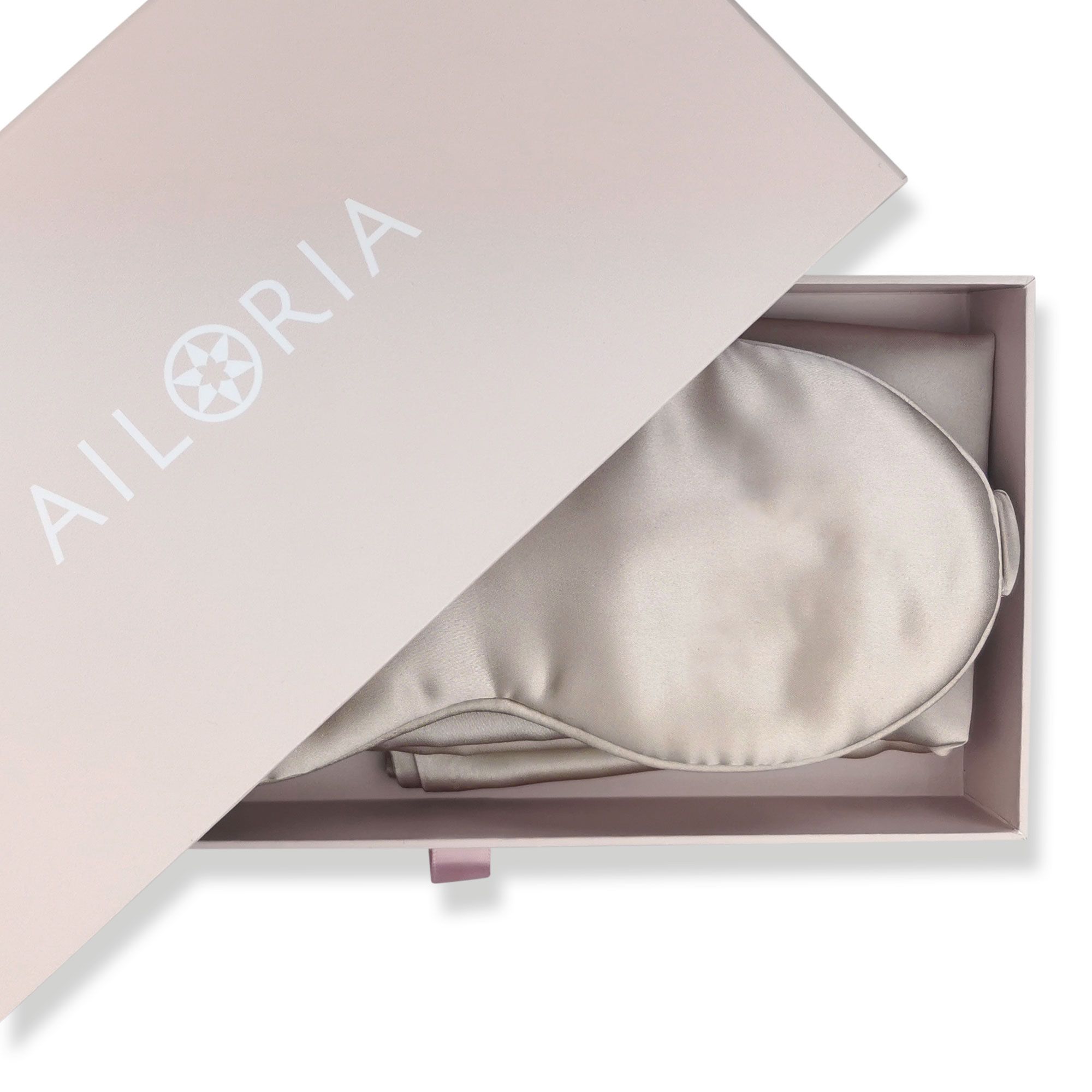 Una maschera per dormire in seta argentata è adagiata in una scatola regalo aperta rosa pallido con il logo "AILORIA".