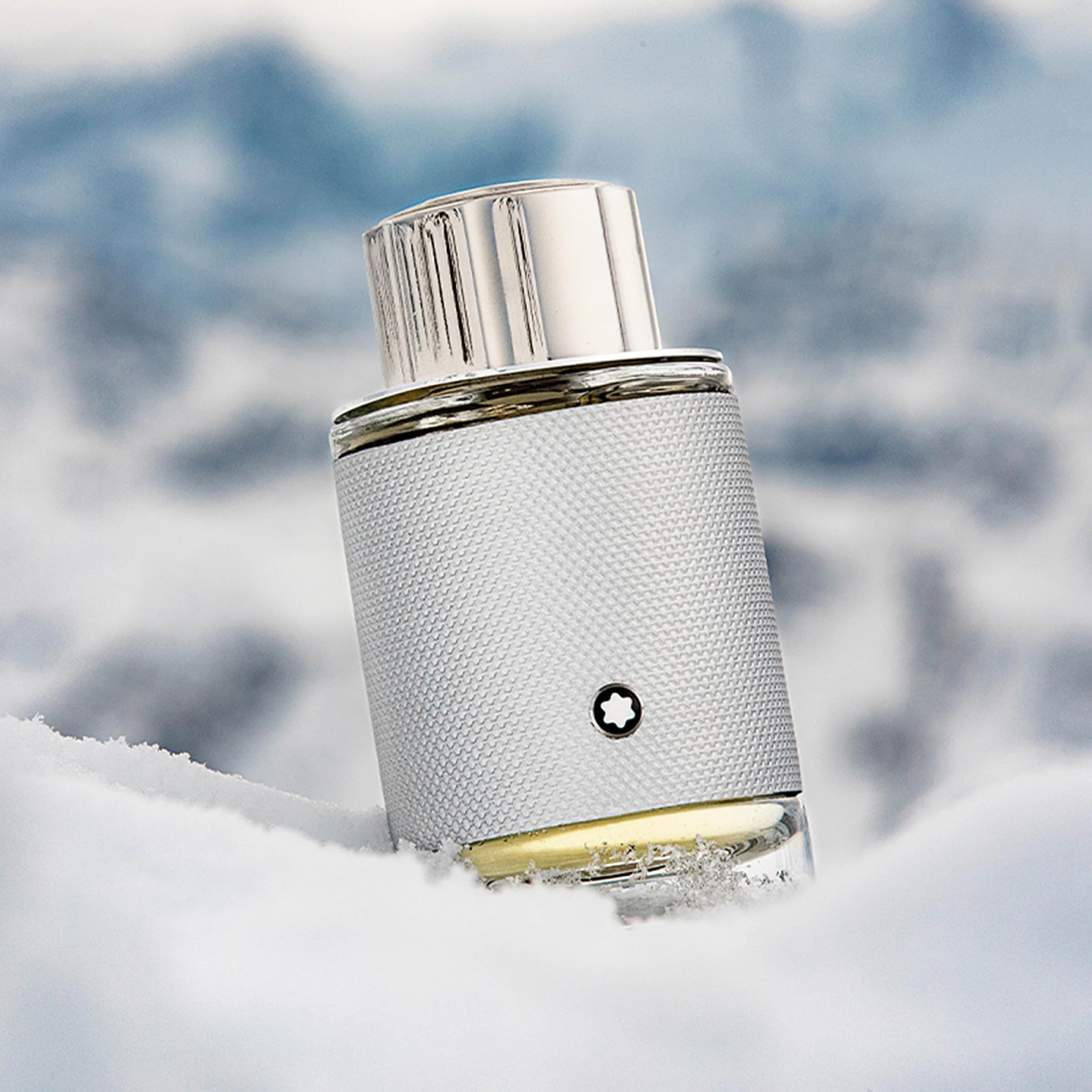 Montblanc Explorer Platinum EdP Nat. Spray. Flacone argentato nella neve. Tappo argentato e flacone con logo. Sfondo: montagne innevate.