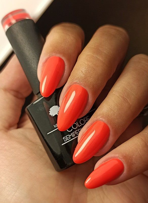 Mano con unghie smaltate e flacone di smalto. Colore Pesca. LCI Cosmetics, smalto semipermanente.