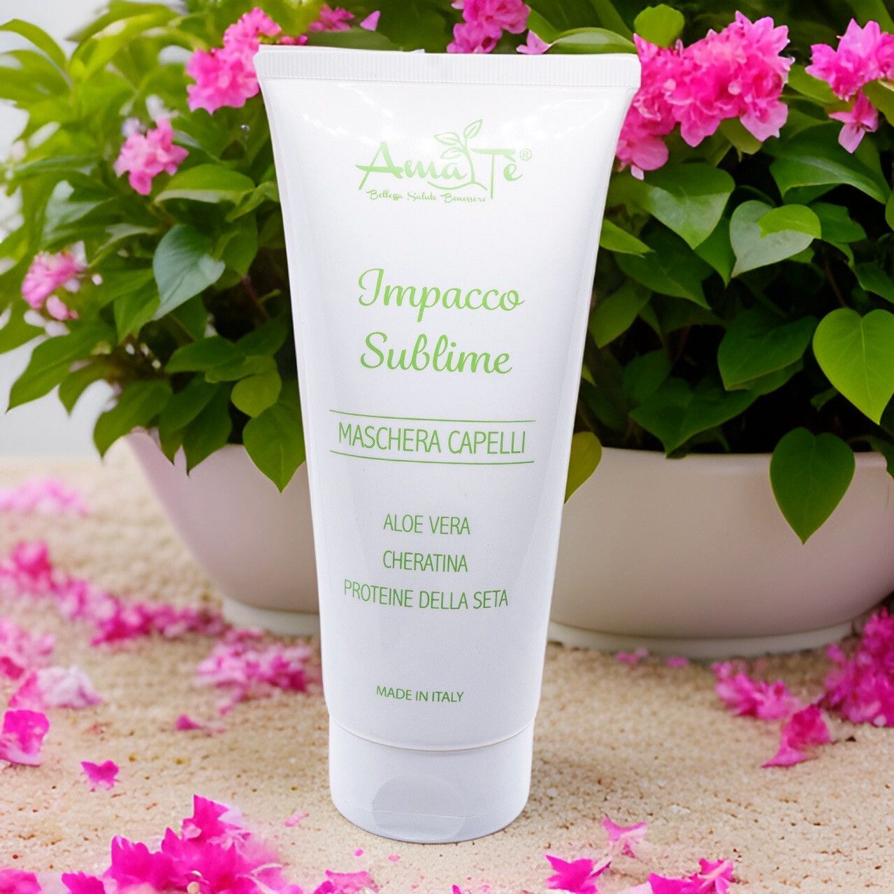 Tubo bianco con testo verde: Amatè, Impacco Sublime, Maschera Capelli. Aloe Vera, Cheratina, Proteine della seta. Con fiori e sabbia.