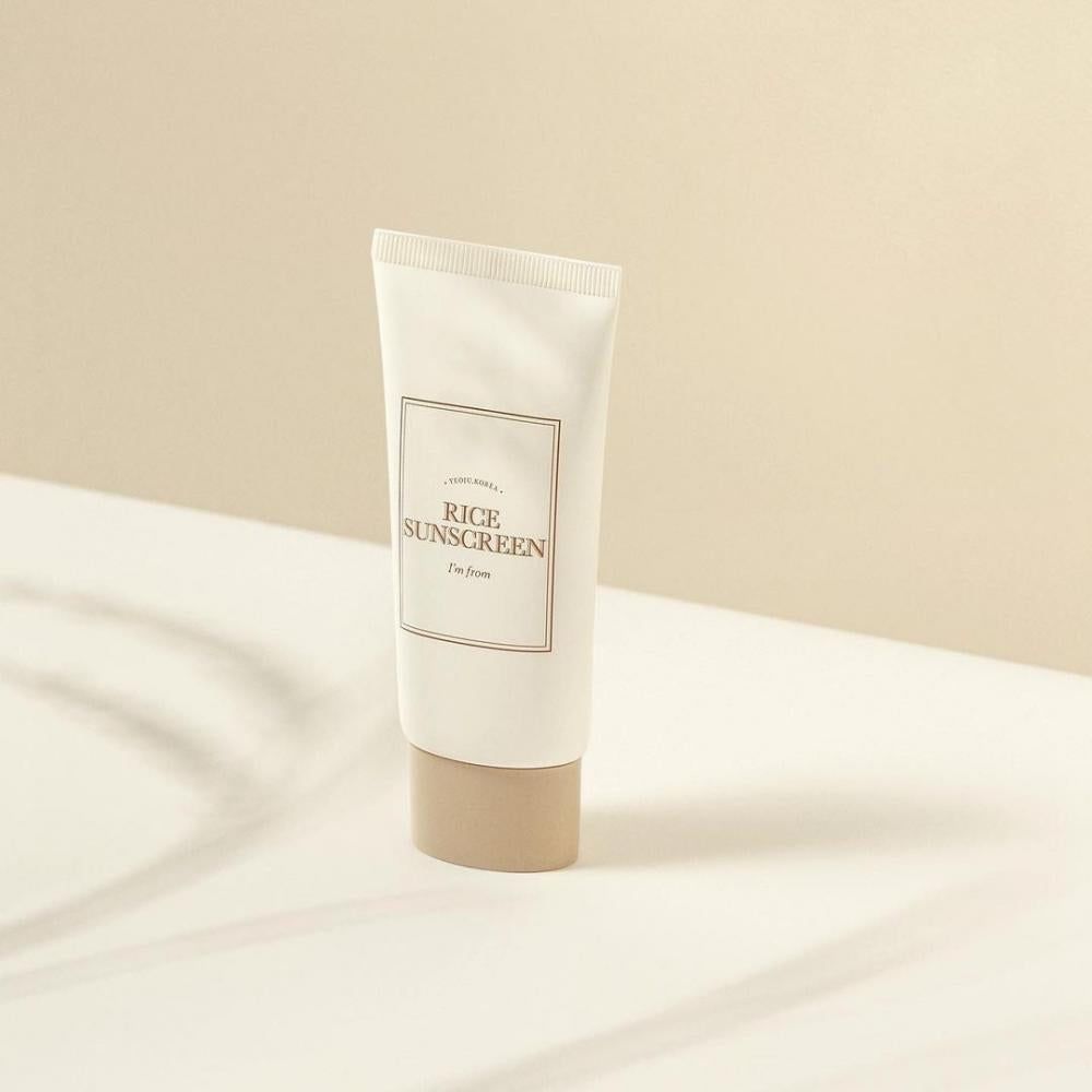 Tubo crema con scritta « Rice Sunscreen » e « I'm from ». Tappo beige su sfondo bianco.
