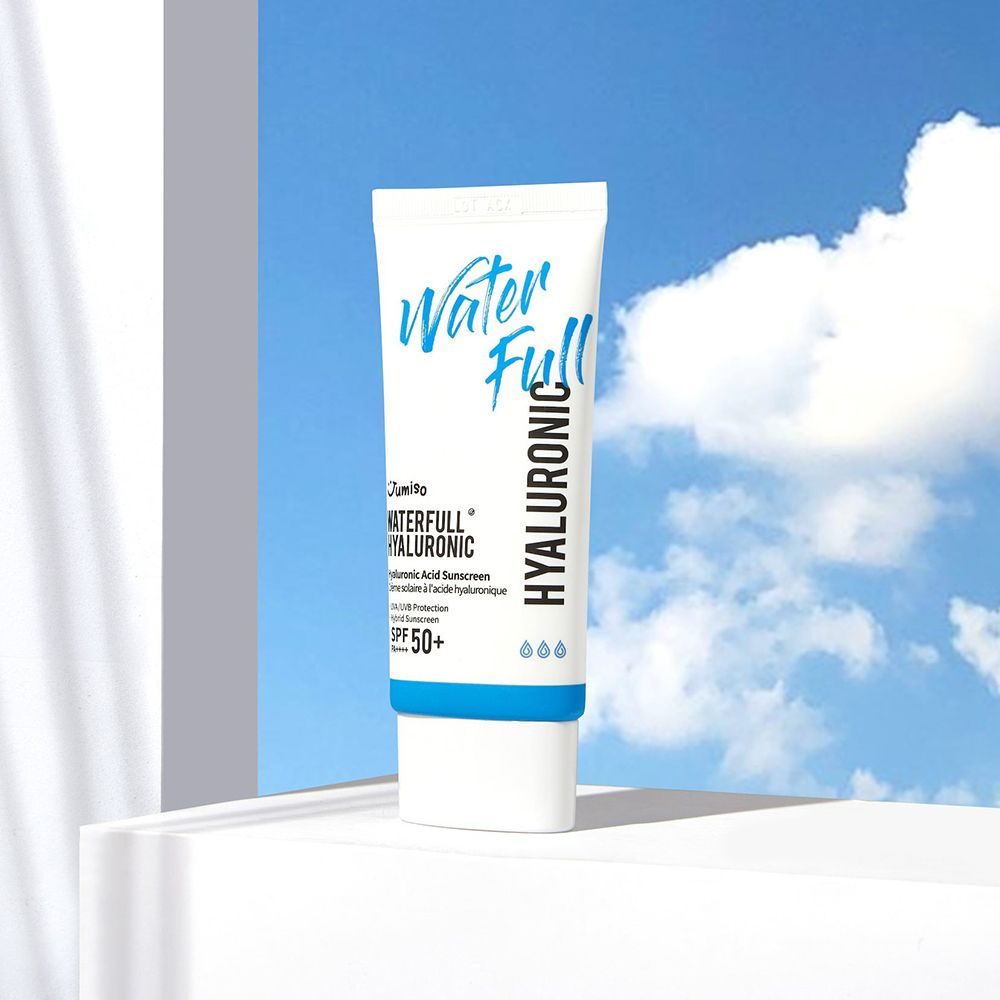 Tubo bianco con tappo blu. Scritta: Water Full, Hyaluronic, SPF 50+. Prodotto su superficie bianca, cielo sullo sfondo.