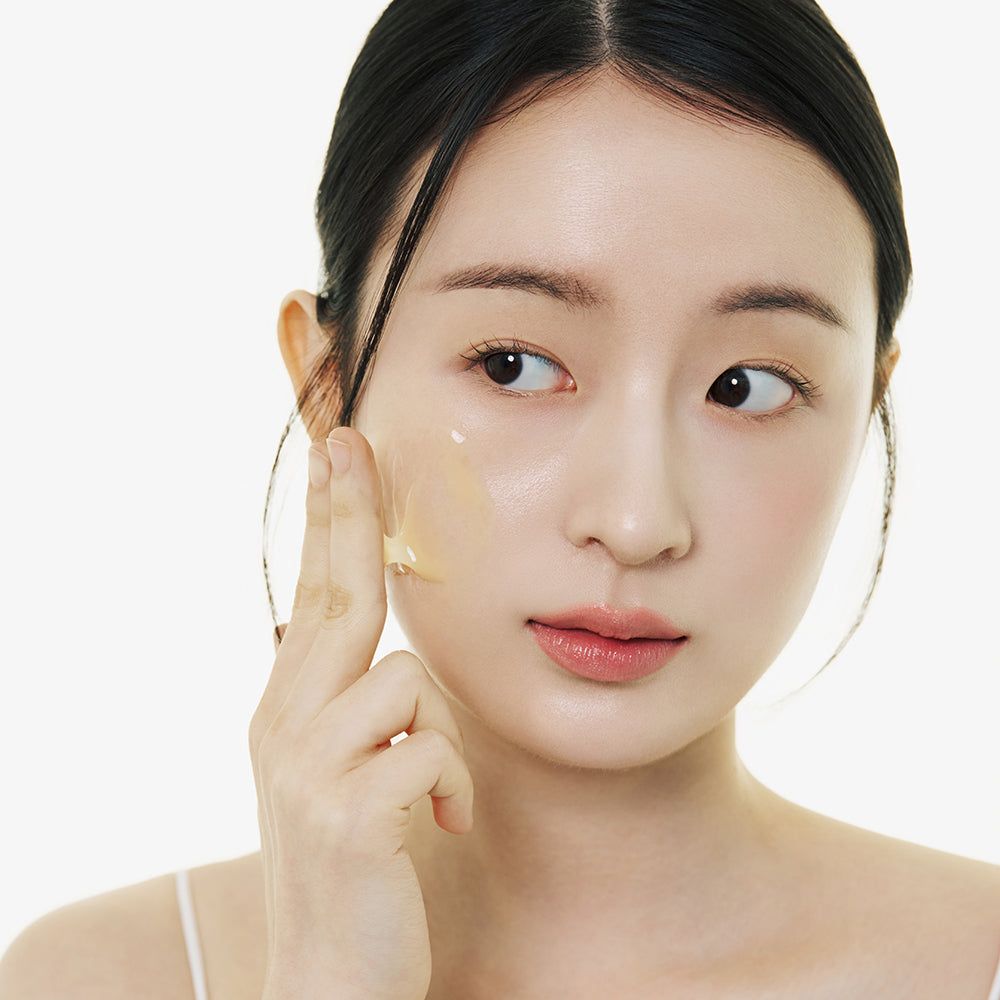 Una donna applica il siero in fiala sulla guancia. Applicazione per la cura della pelle.