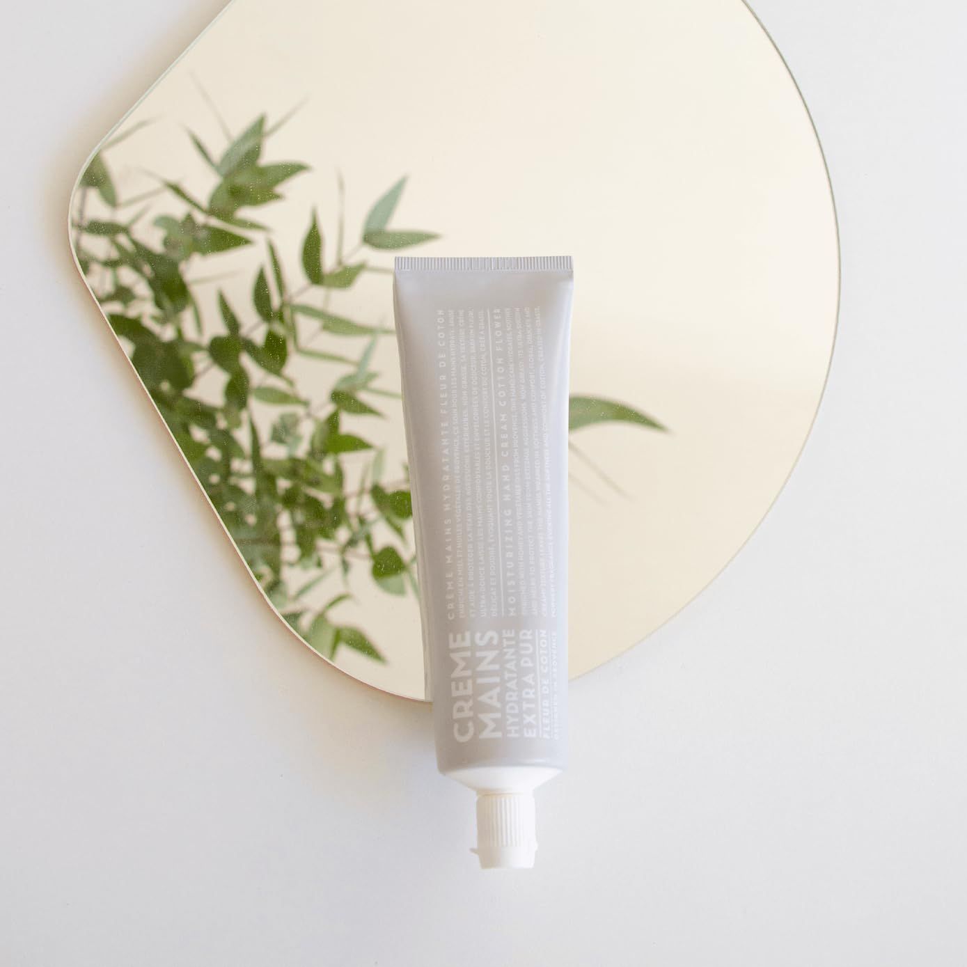 Tubo grigio con tappo bianco, etichettato 'CREME MAINS HYDRATANTE EXTRA PUR'.