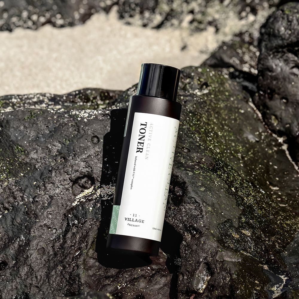 Flacone marrone con tappo nero. Scritta: Toner, Active Clean. Posizionato su rocce.