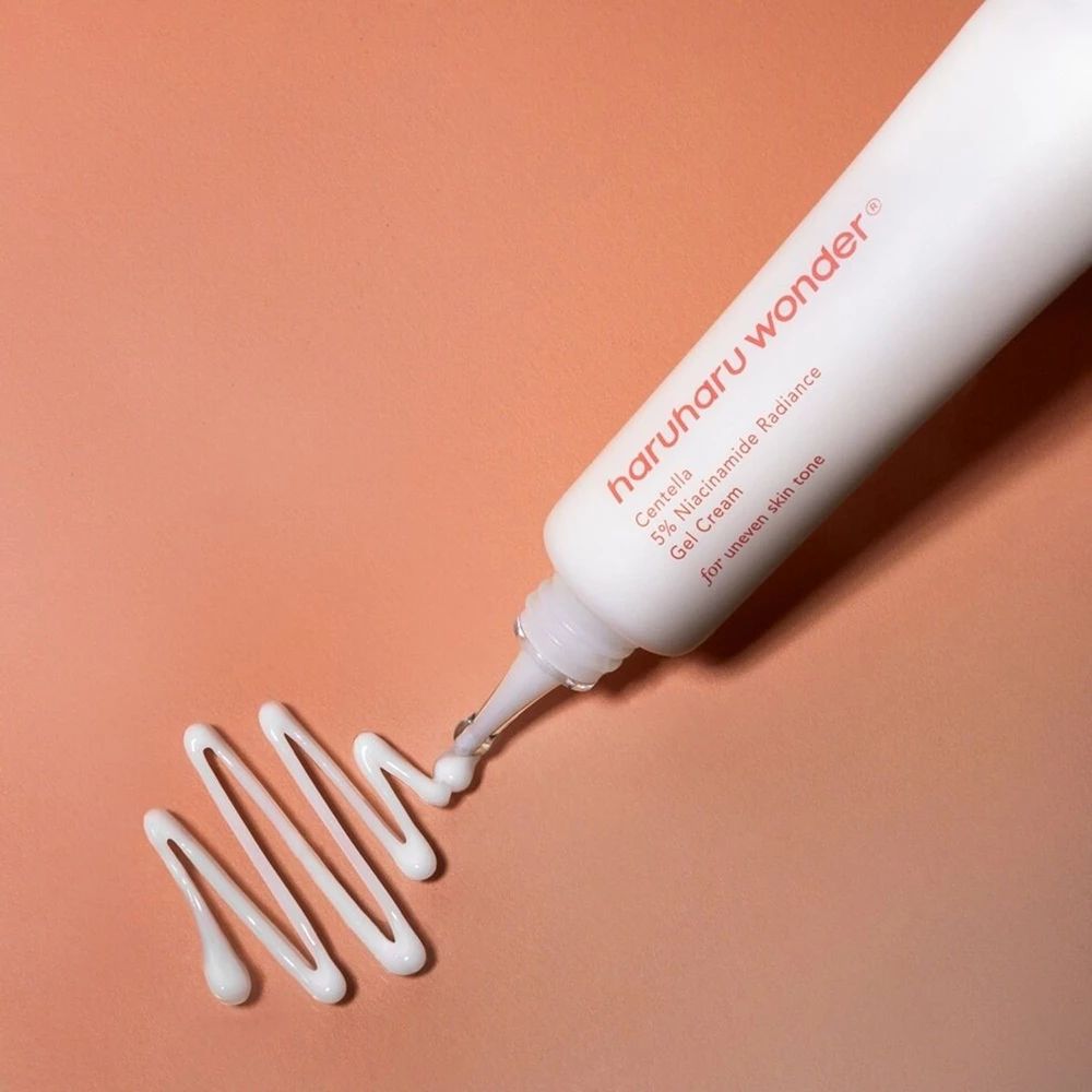 Tubo bianco, prodotto spremuto dall'apertura. Nome del prodotto e testo sul tubo.