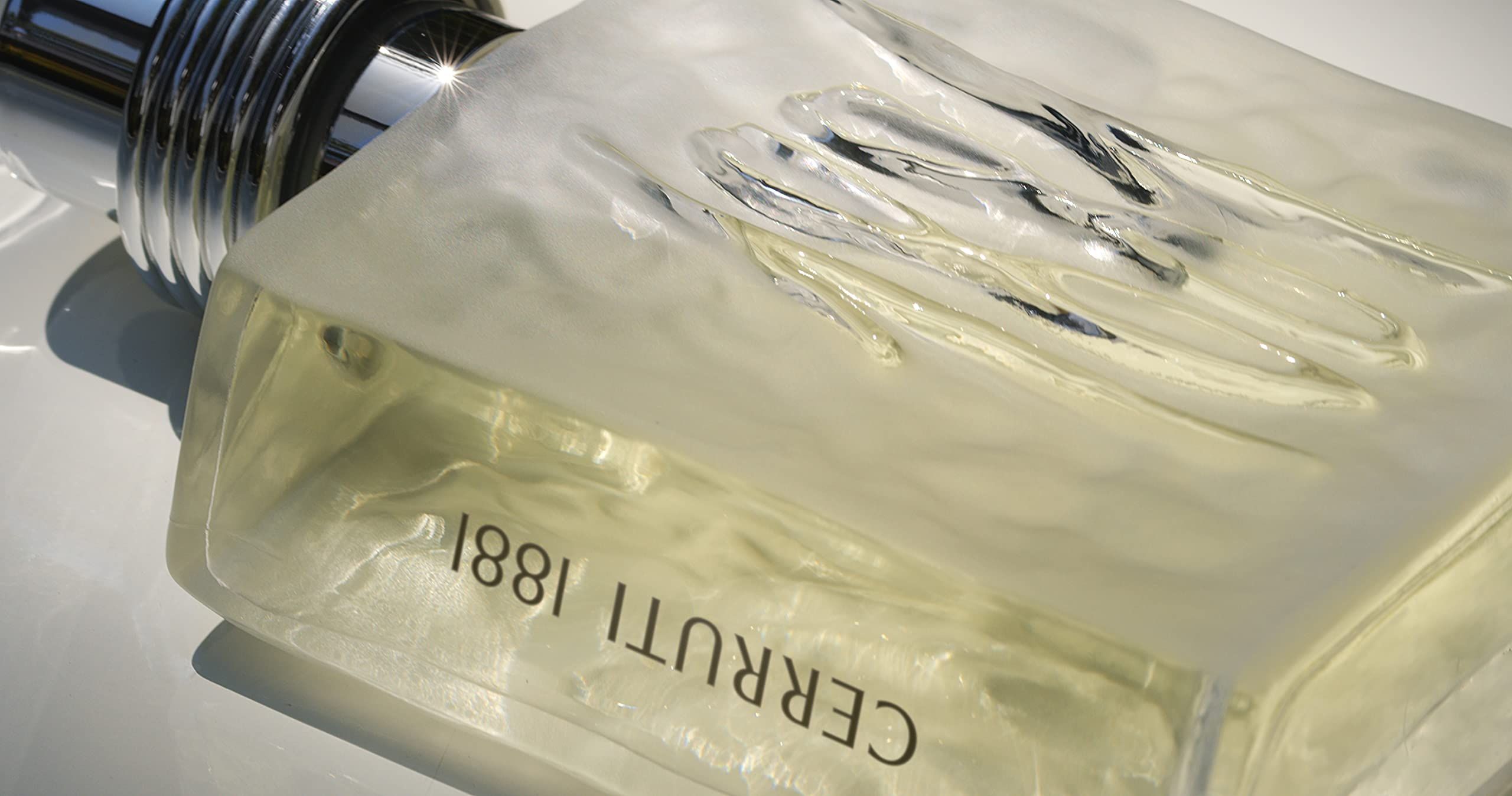Primo piano di un flacone. Il numero 1881 è impresso sul davanti. Il flacone è riempito con un liquido giallastro. Il nome Cerruti 1881 è visibile.