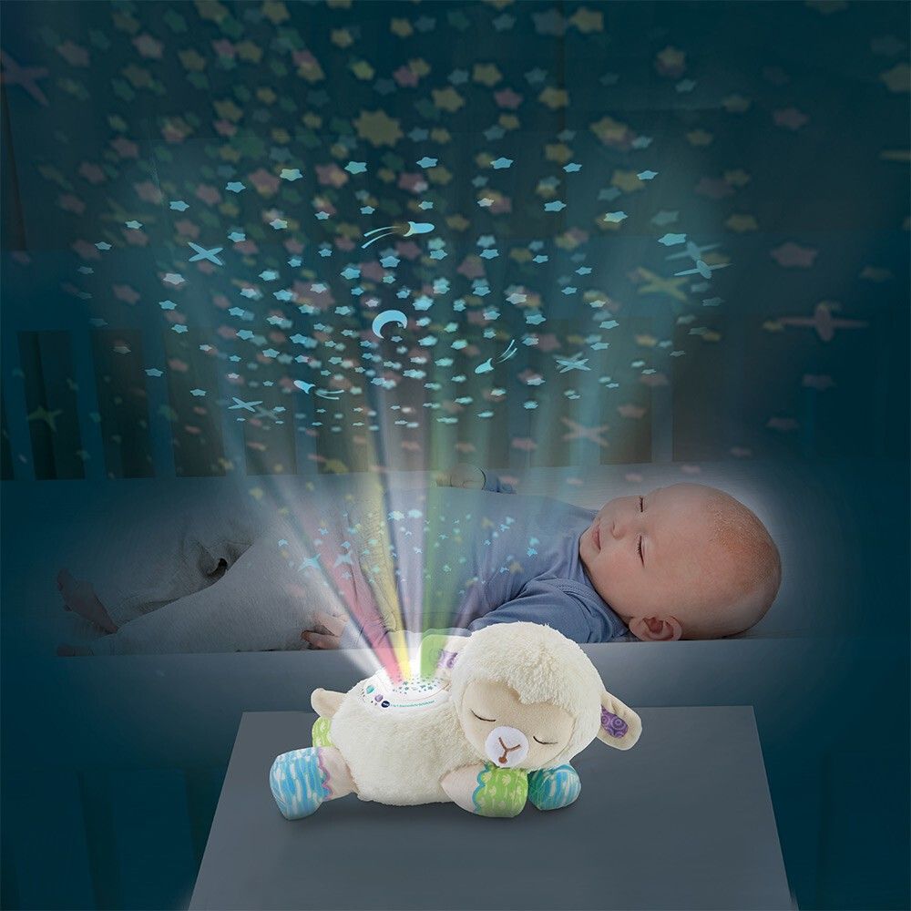 Bambino a letto, proiezione di stelle sul soffitto. Luce notturna a forma di pecora sul comodino.