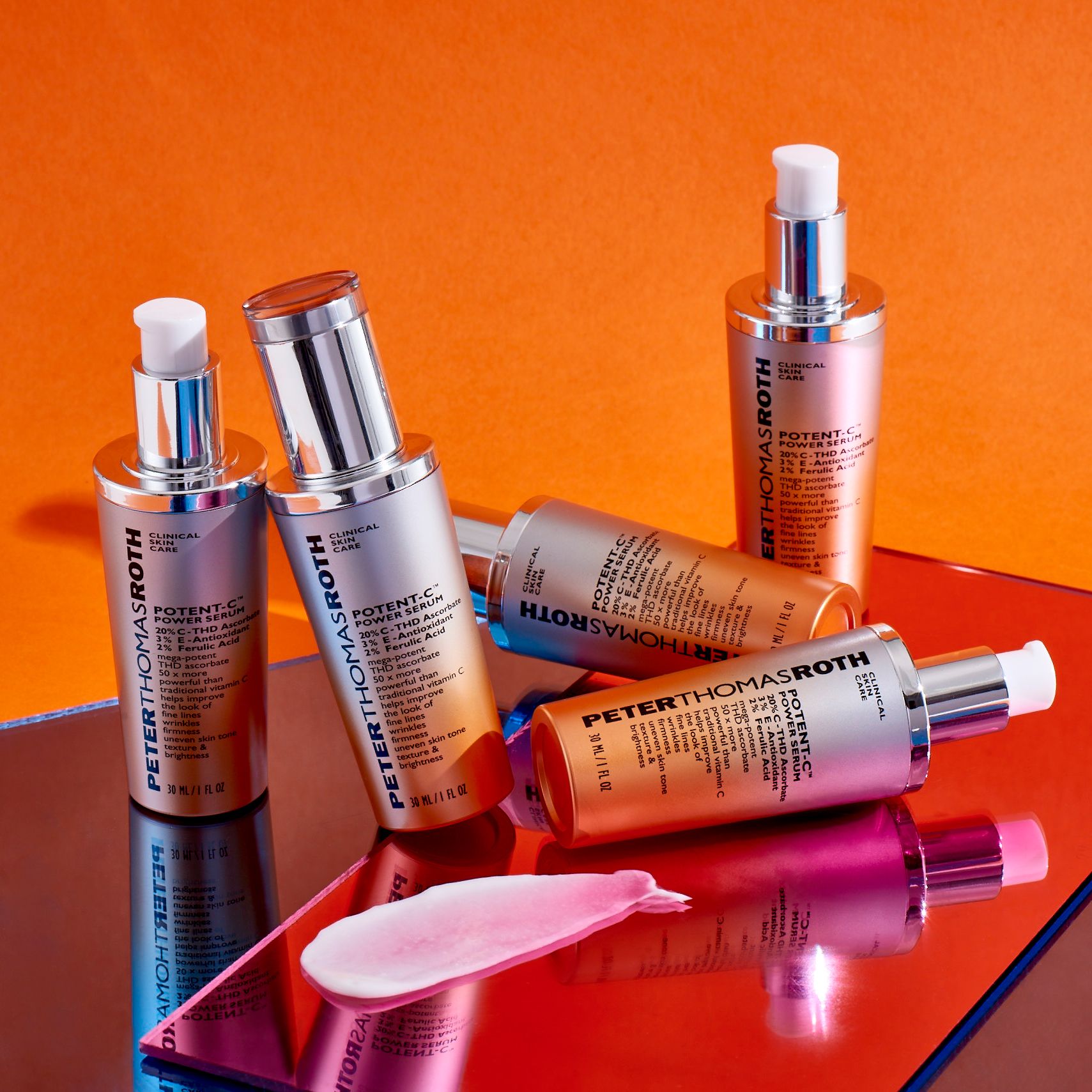 Diversi flaconi di siero. Scritta: Potent-C Power Serum. Tappi argentati e sfumatura arancione. Su sfondo arancione.