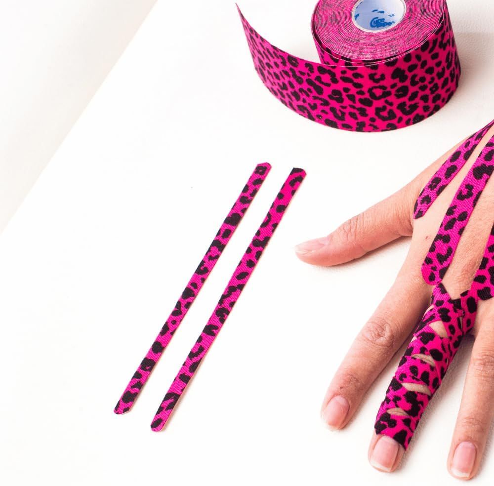Mano con kinesio tape rosa con motivo leopardato. Due strisce tagliate sono accanto.