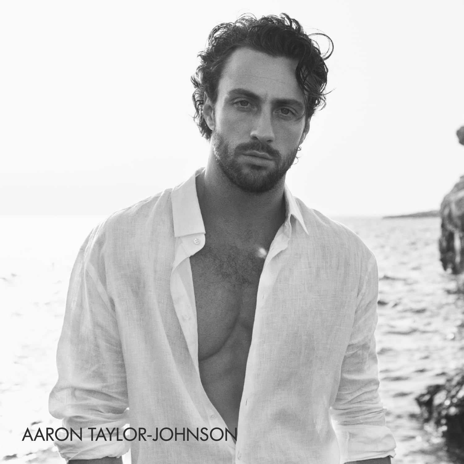 Ritratto in bianco e nero di Aaron Taylor-Johnson con una camicia bianca.