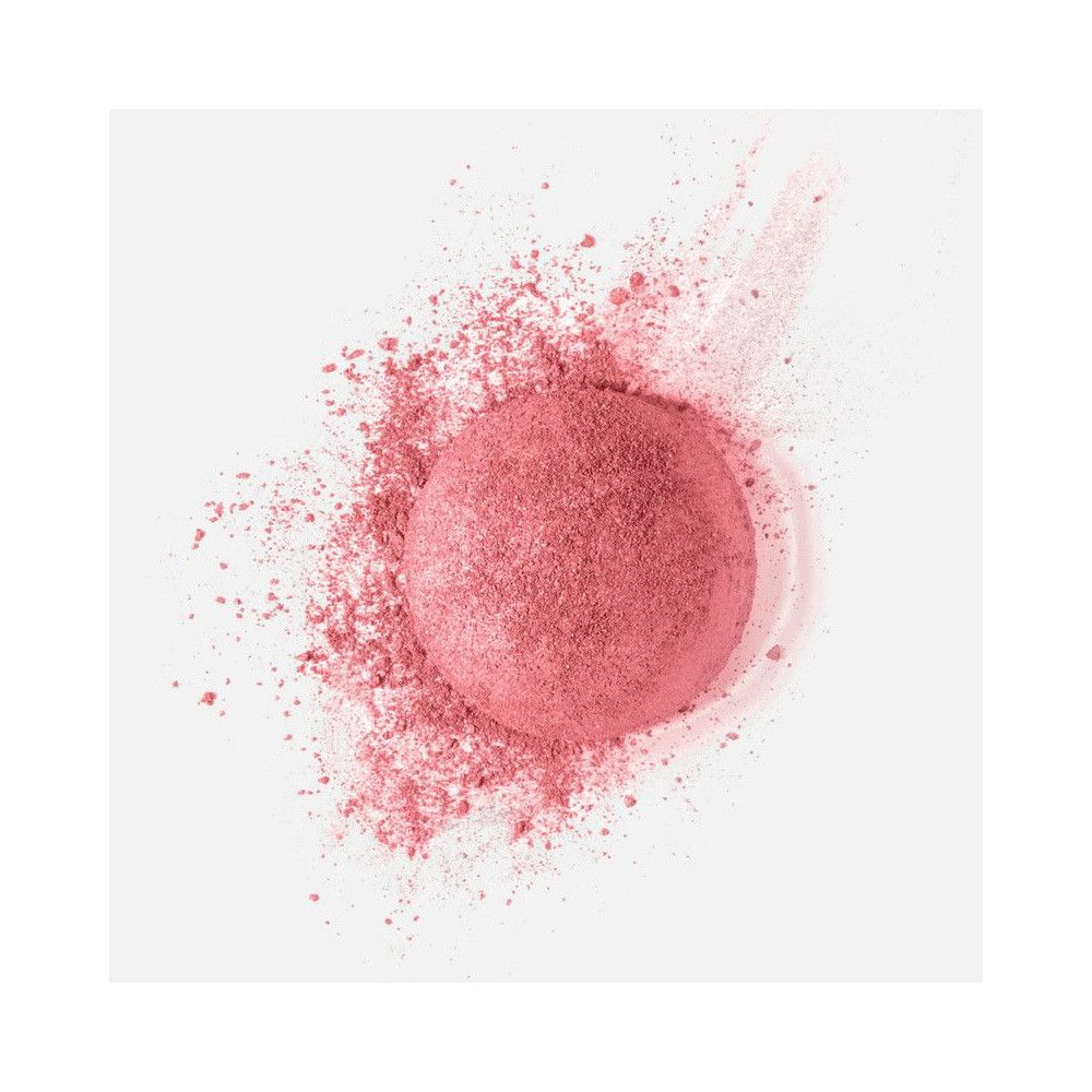 Fard in polvere rosa, forma rotonda, circondato da particelle di polvere. Sfondo bianco.