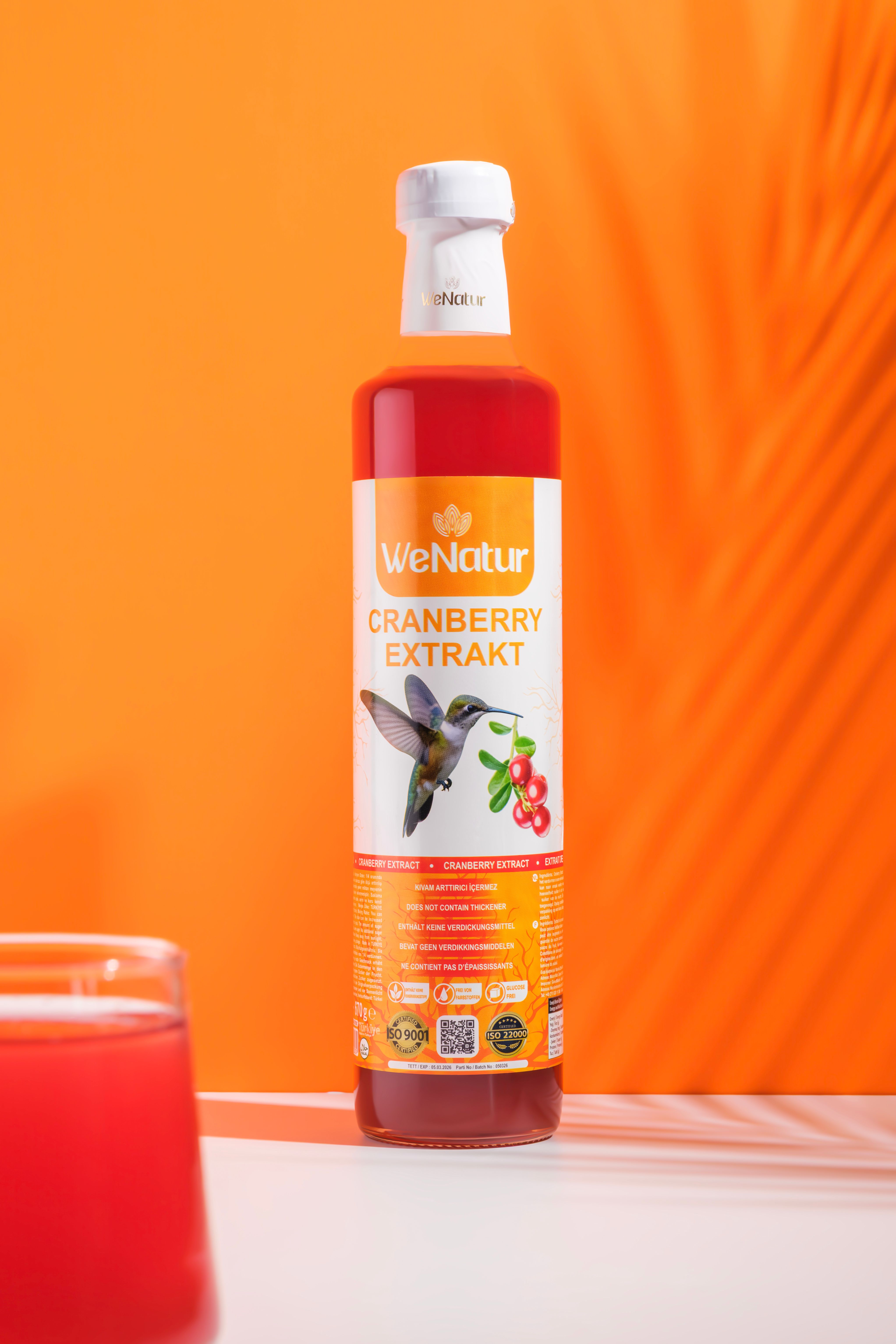 Bottiglia di estratto di mirtillo rosso, etichetta con colibrì e bacche.