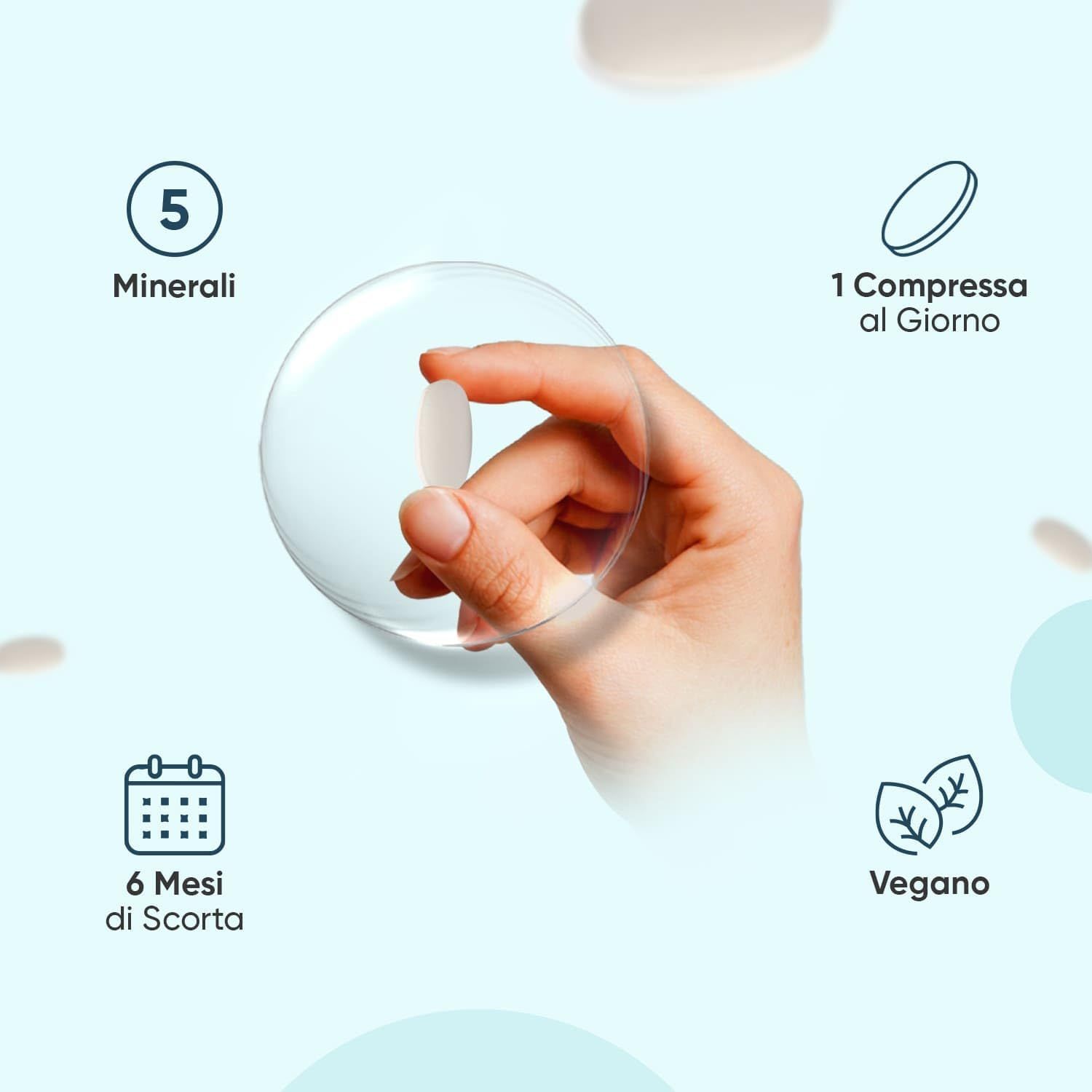 Mano che tiene una compressa. Testo: 5 minerali, 6 mesi di scorta, 1 compressa al giorno, Vegano.