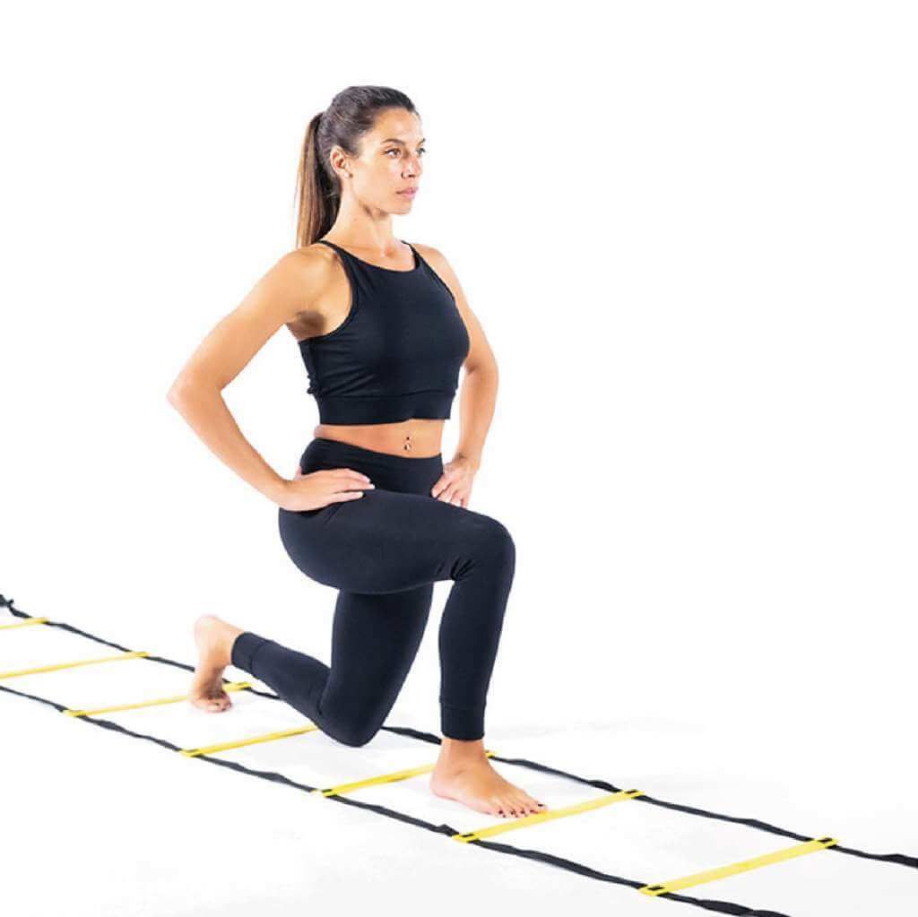 Donna che si allena su una scala per allenamento gialla. Esegue affondi.