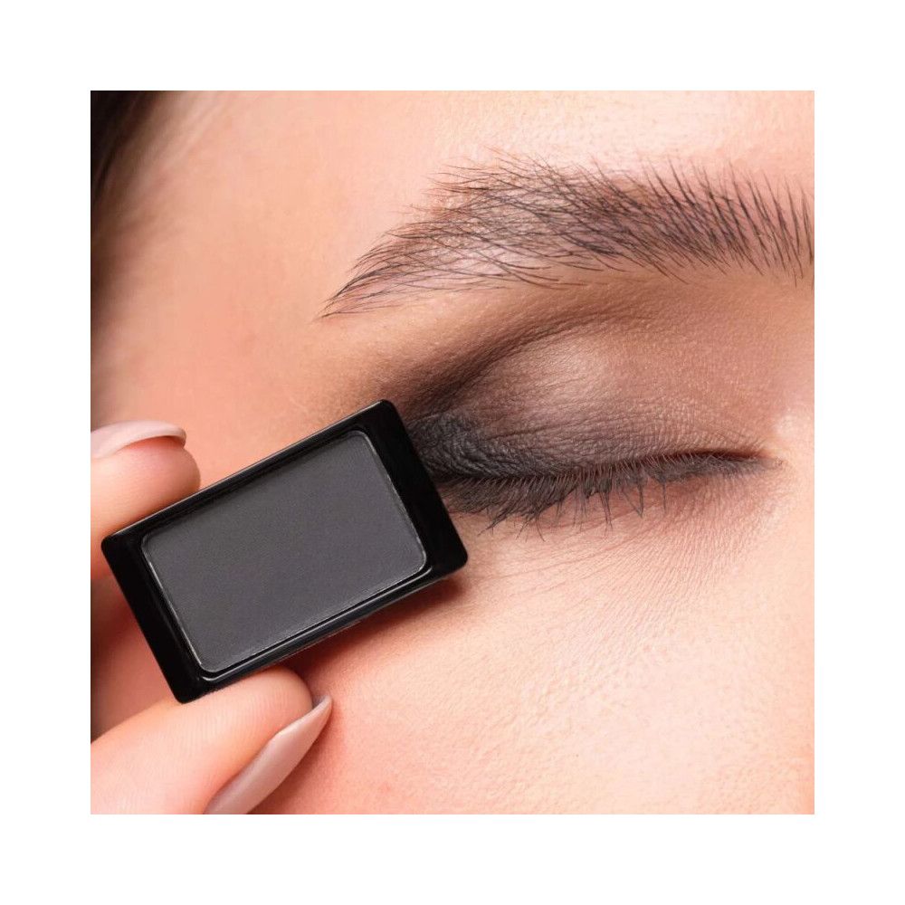 Ombretto Artdeco 503 Matt Black. Applicazione sulla palpebra. Il prodotto è tenuto in mano. Colore nero.