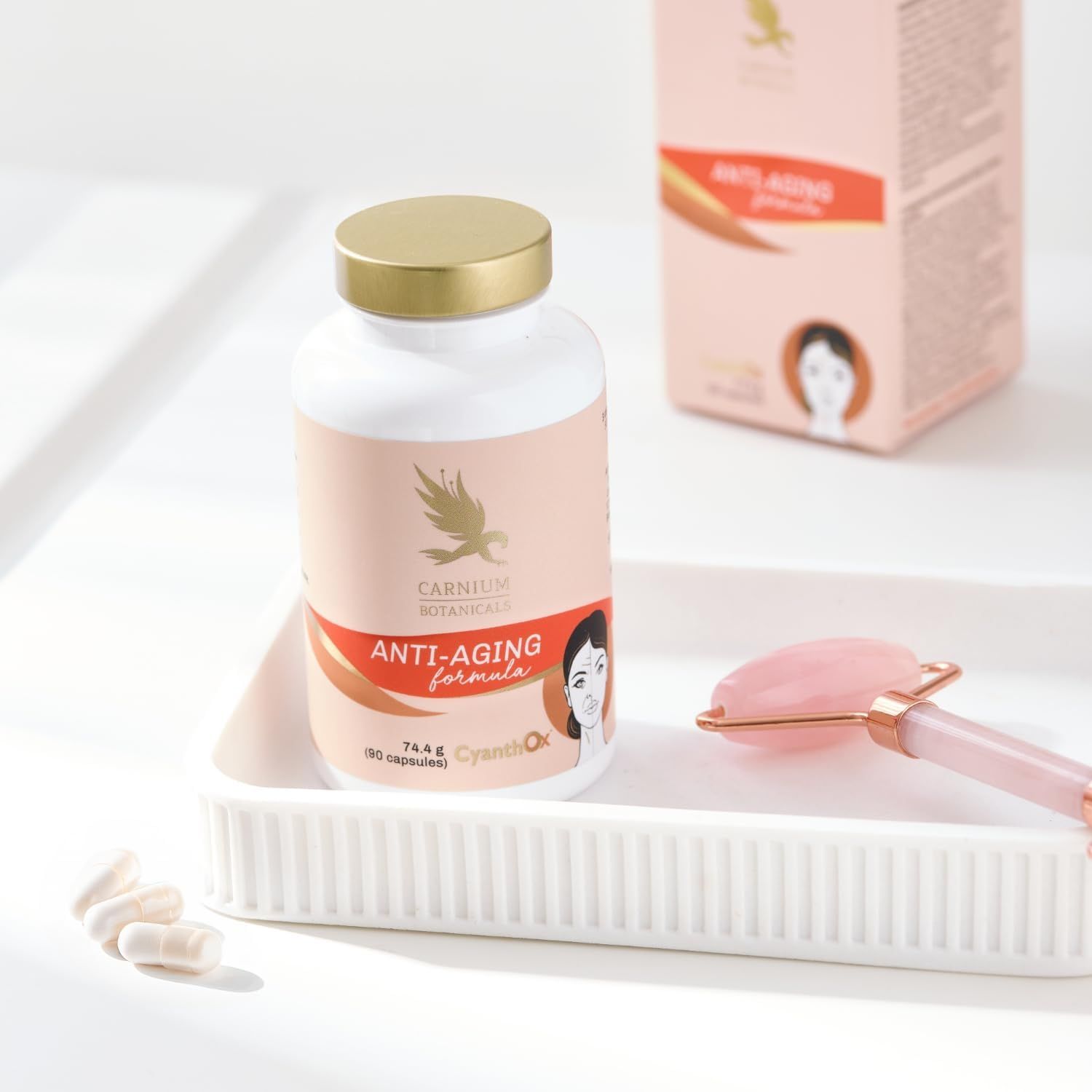 Flacone con tappo dorato in ciotola bianca. Scritta: Anti-Aging formula. Rullo di quarzo rosa accanto.
