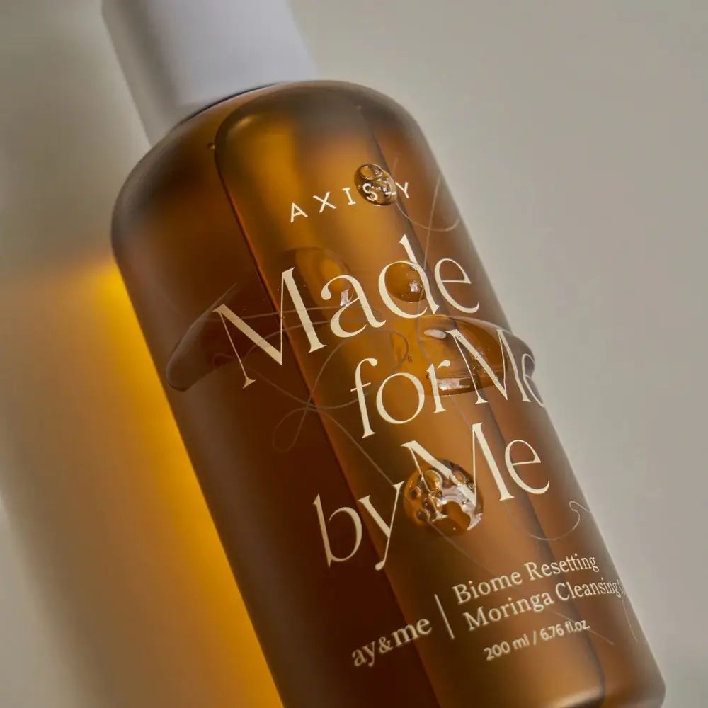 Flacone marrone con erogatore bianco. Scritta: AXIS-Y, Made for Me by Me, Biome Resetting Moringa Cleansing Oil.