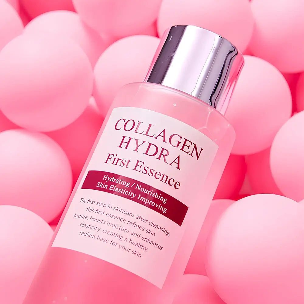 Flacone trasparente con liquido rosa. Scritta: Collagen Hydra First Essence. Sfondo: palline rosa.