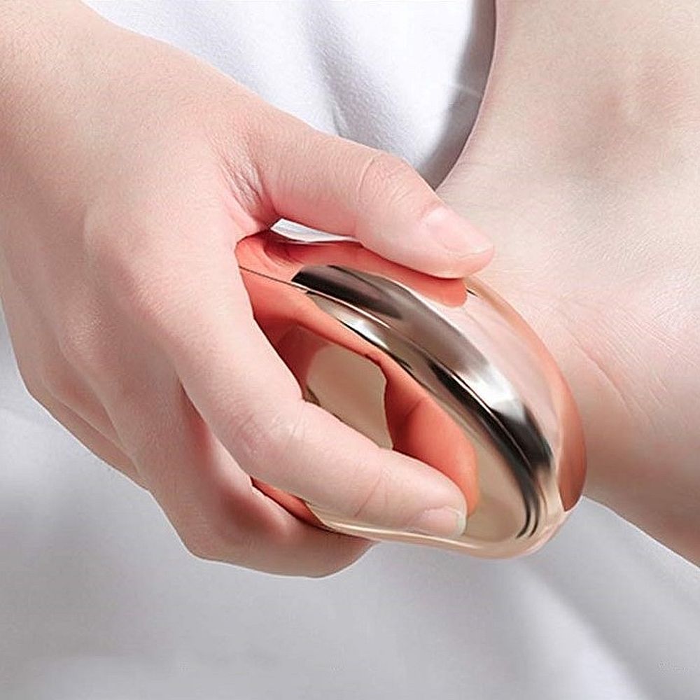 Mano che tiene un dispositivo per pedicure dorato. Dispositivo applicato sul piede. Cura della pelle.