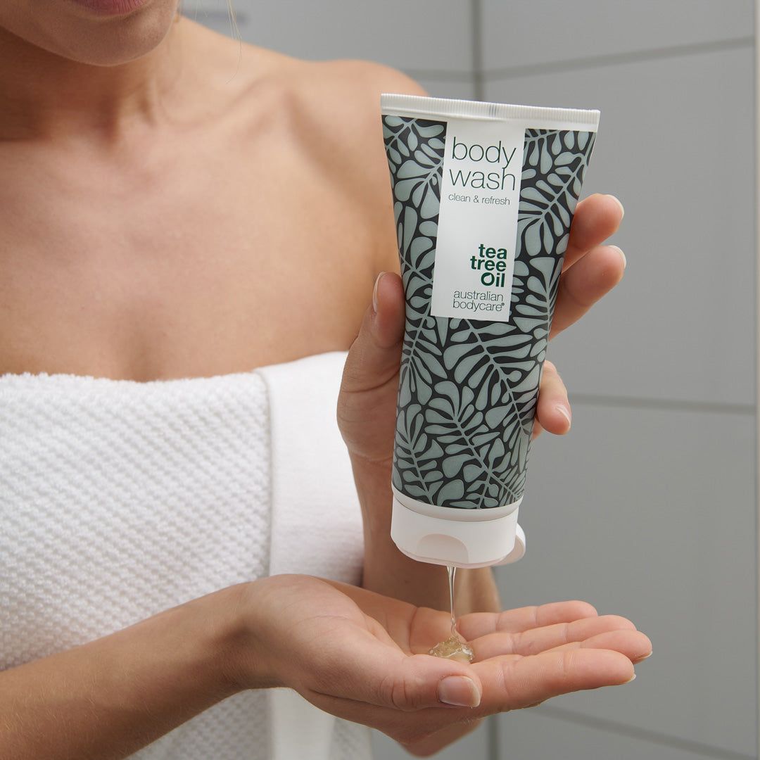 Persona che tiene un tubetto di Body Wash. Il prodotto viene versato sul palmo. Marchio: Australian Bodycare. Contesto: bagno.