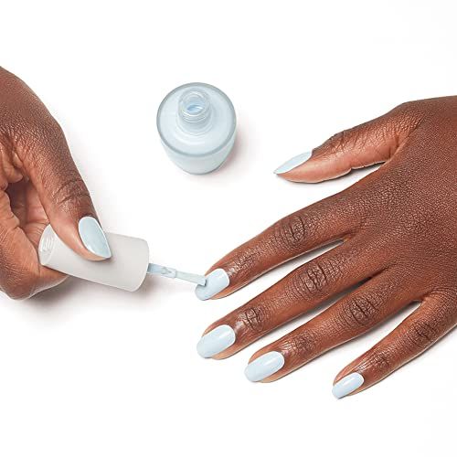 Mani che dipingono le unghie di azzurro. Flacone e pennello di smalto. Processo di manicure.