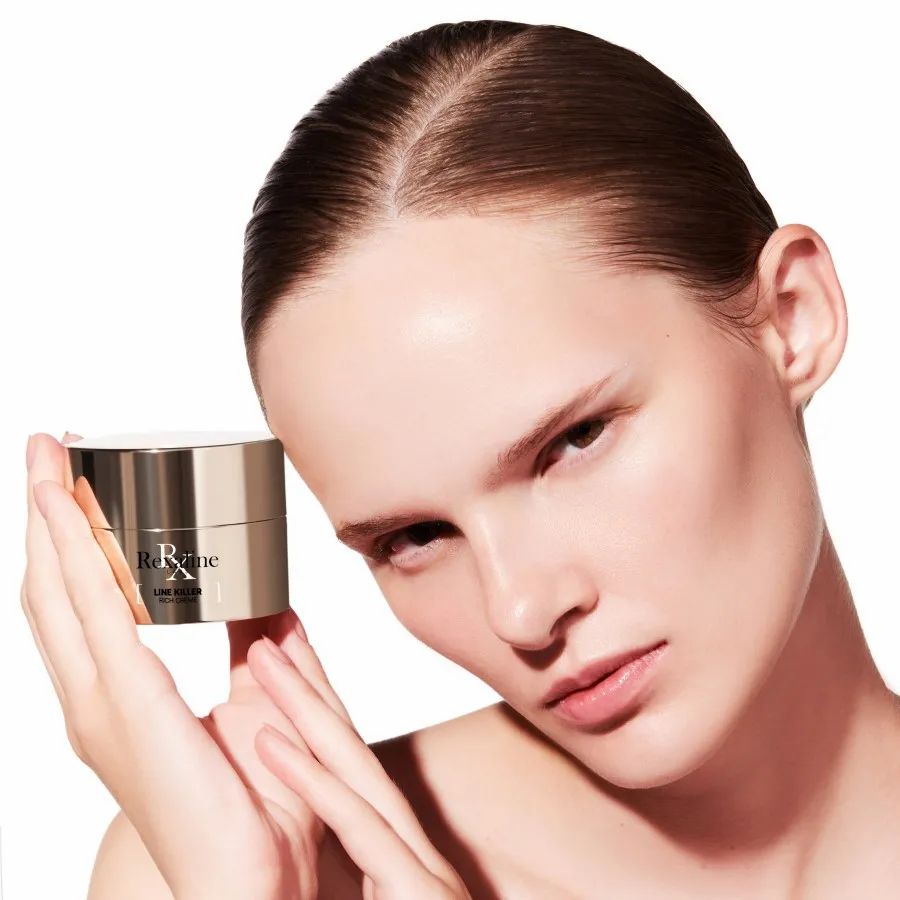 Donna che tiene un vasetto di crema. Sul vasetto c'è scritto Rexaline Line Killer Rich Creme.