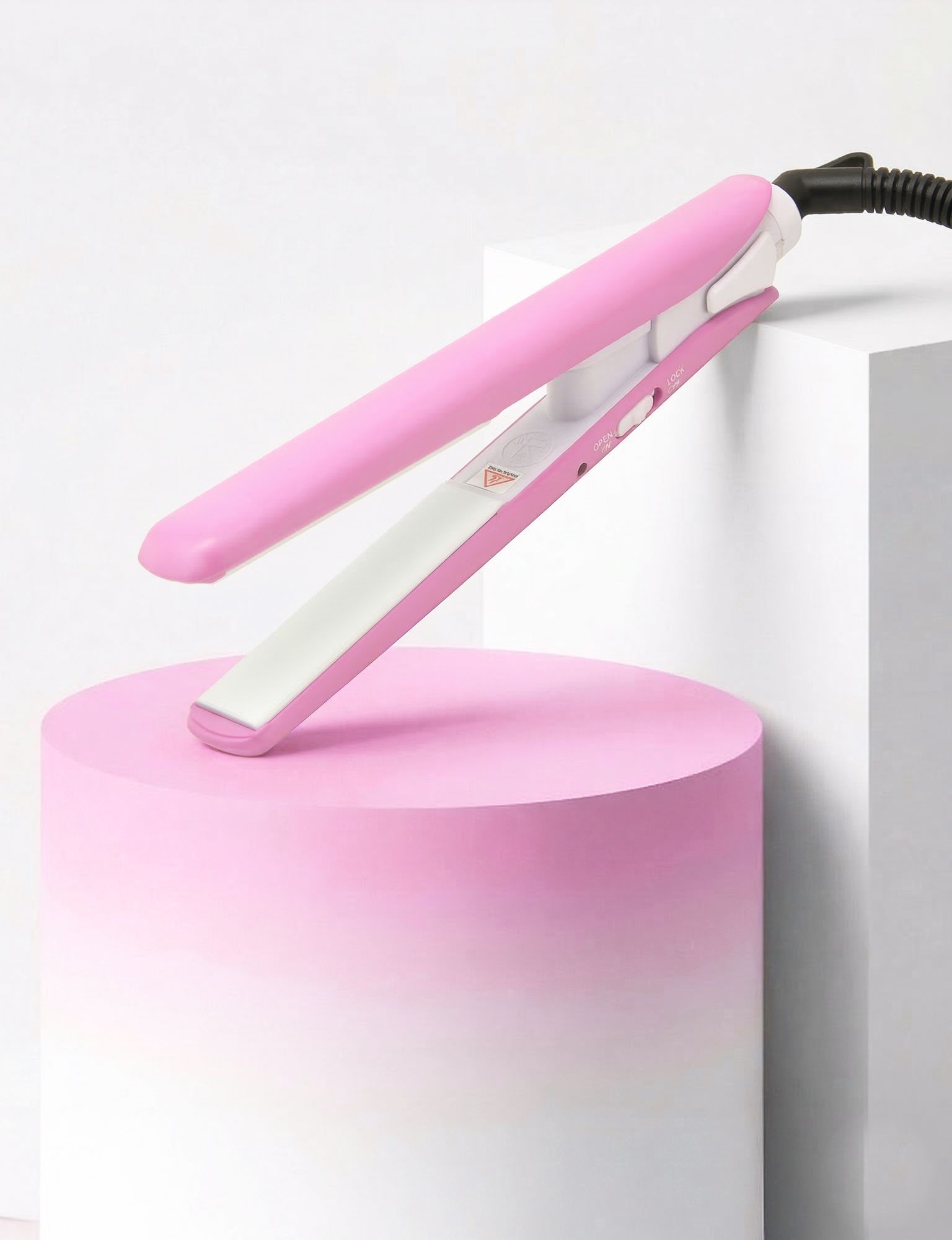Piastra per capelli rosa su piedistallo rosa. Elemento riscaldante in ceramica bianca. Cavo nero. Effetto schiarente.