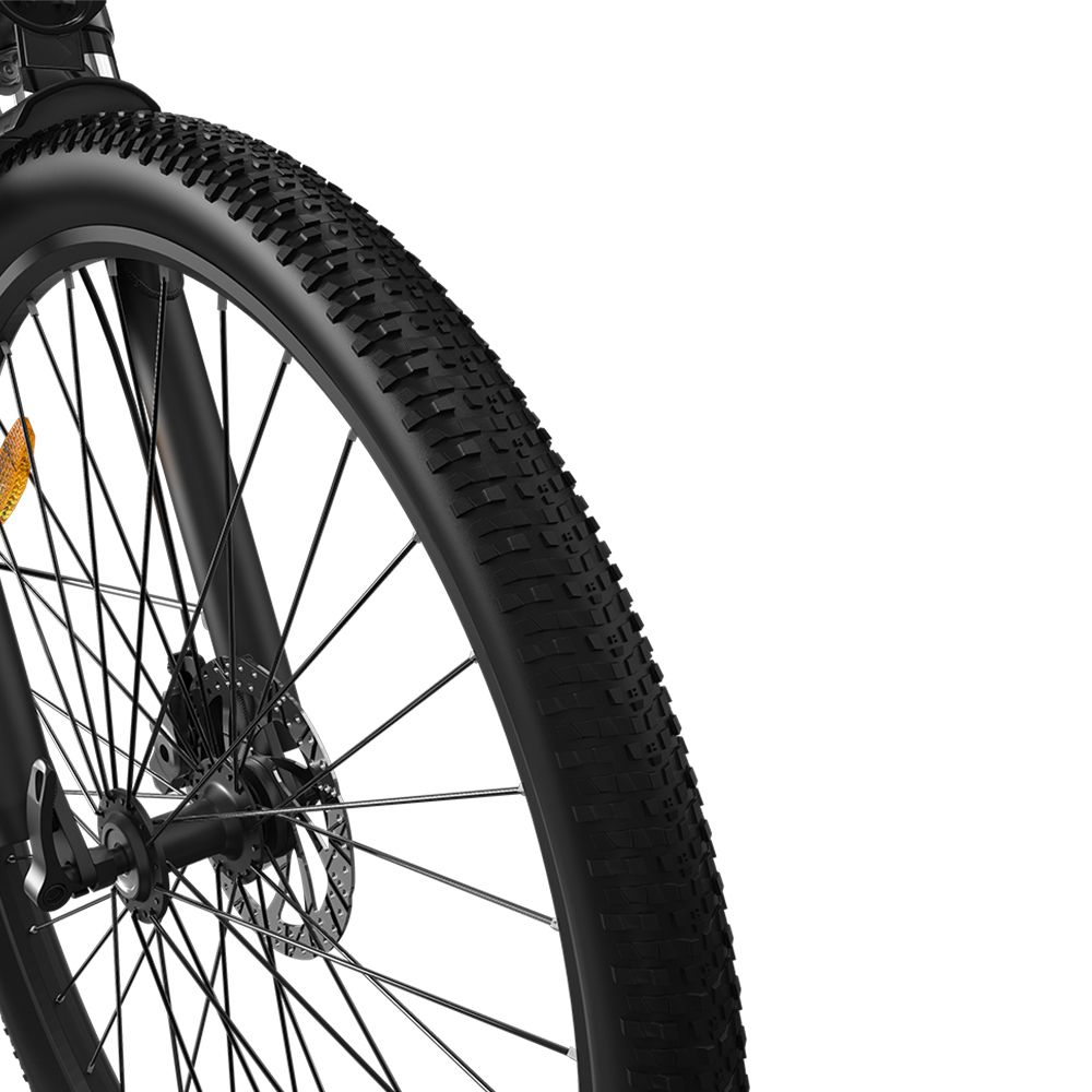 Primo piano della ruota anteriore di una bicicletta elettrica nera. Pneumatico nero con battistrada. Raggi e disco freno visibili.