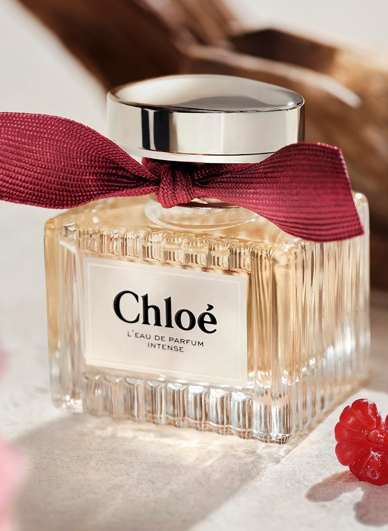 Flacone, tappo argentato, fiocco rosso. Etichetta "Chloé L'EAU DE PARFUM INTENSE".