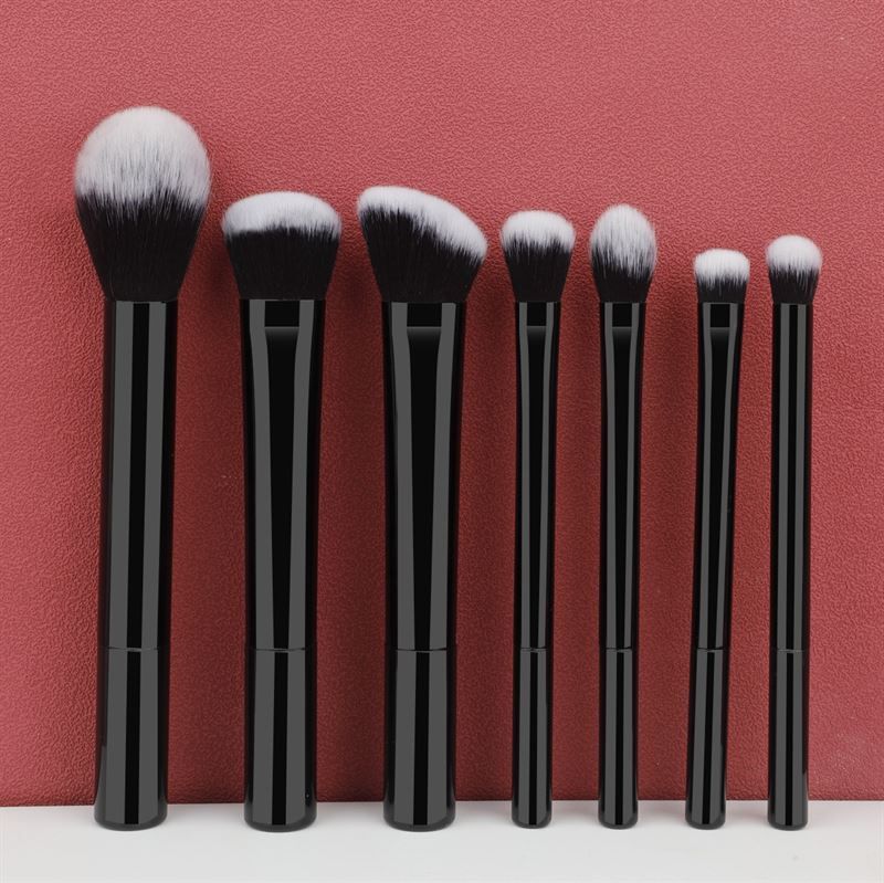 Set di sette pennelli per trucco neri con setole bianche. Diverse forme e dimensioni.