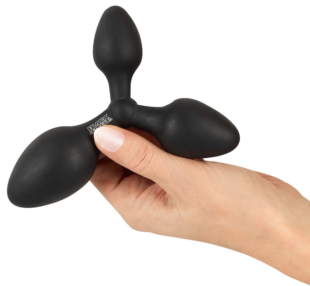 Plug anale nero a tre punte. Tre estremità coniche collegate da un nodo centrale. Tenuto in mano.